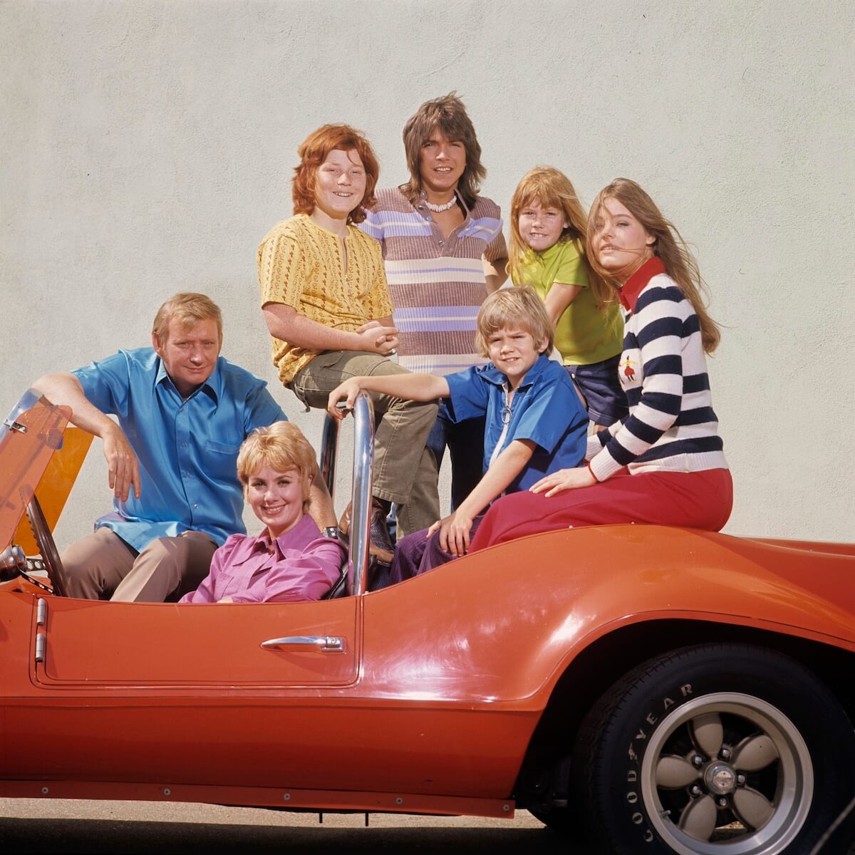 The cast of 'The Partridge Family sitting n a red Corvette