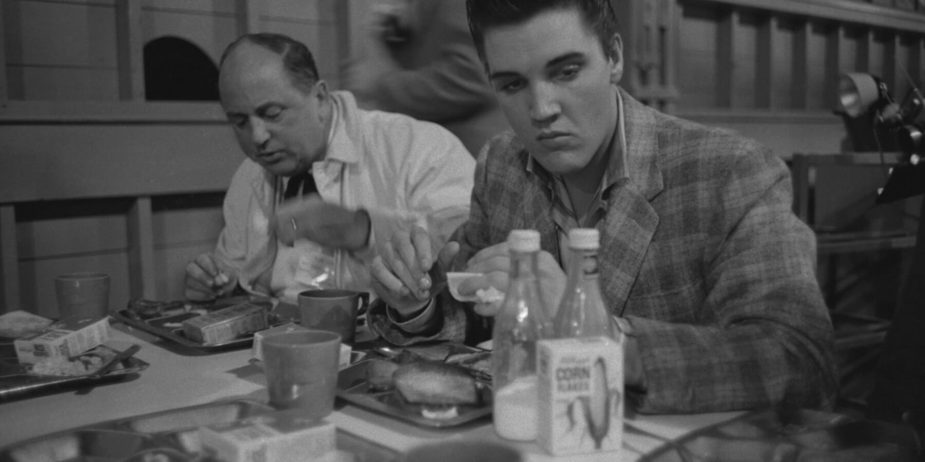 Elvis Presley eats breakfast the day he was conscripted into the US Army with Colonel Tom Parker.