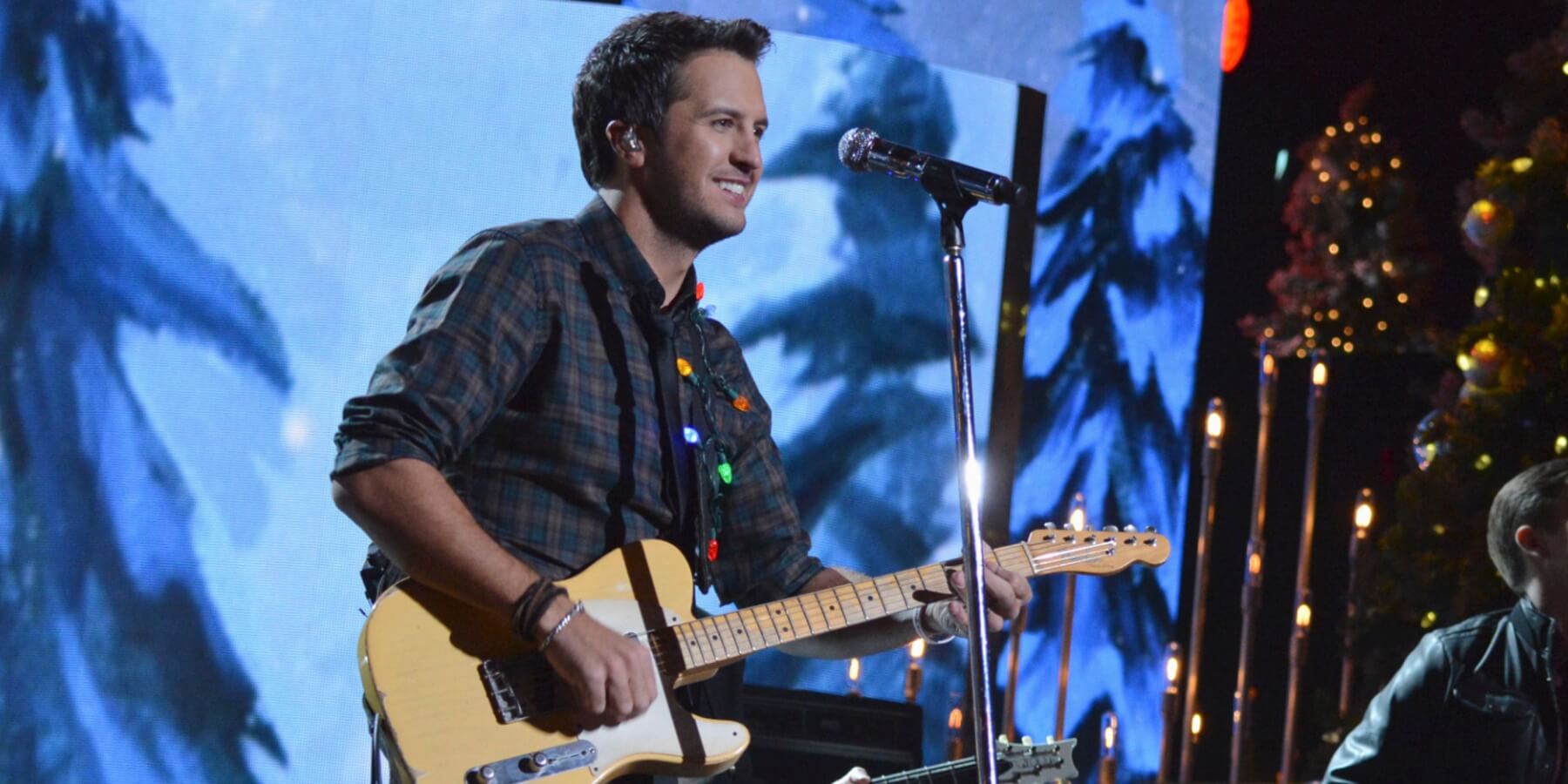 Luke Bryan performs in front of a Christmas tree.