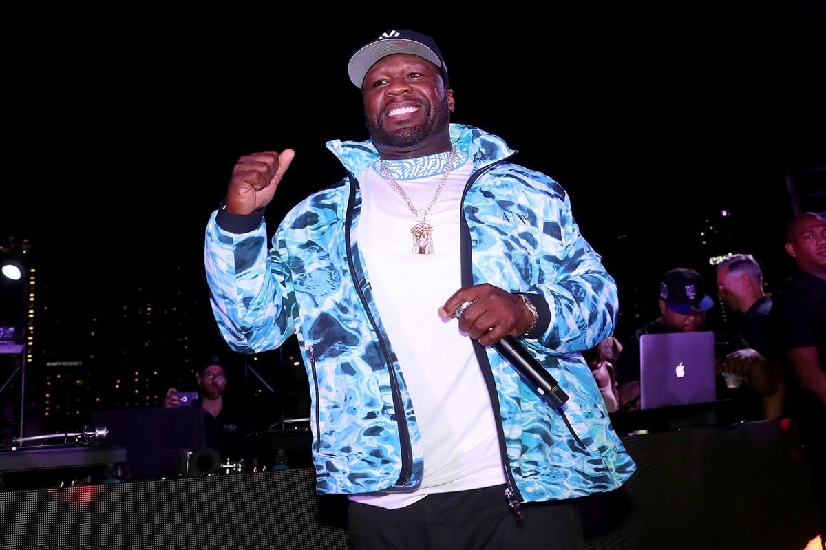 50 Cent posing in a blue jacket and white t-shirt while he performs during the Celia Cruz x Skott Marsi NFT Launch at ITG Miami.