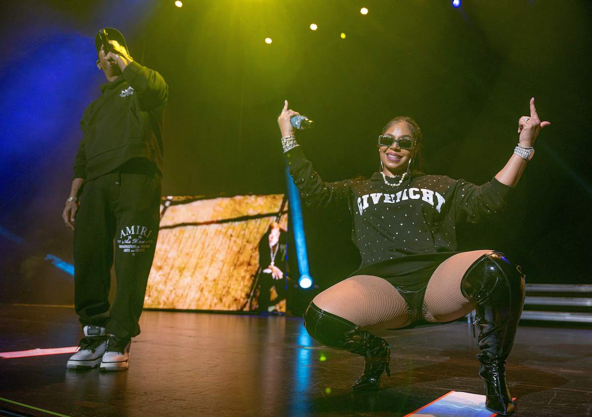 Ashanti squats on stage with her hands in the air while Ja Rule raps into the mic