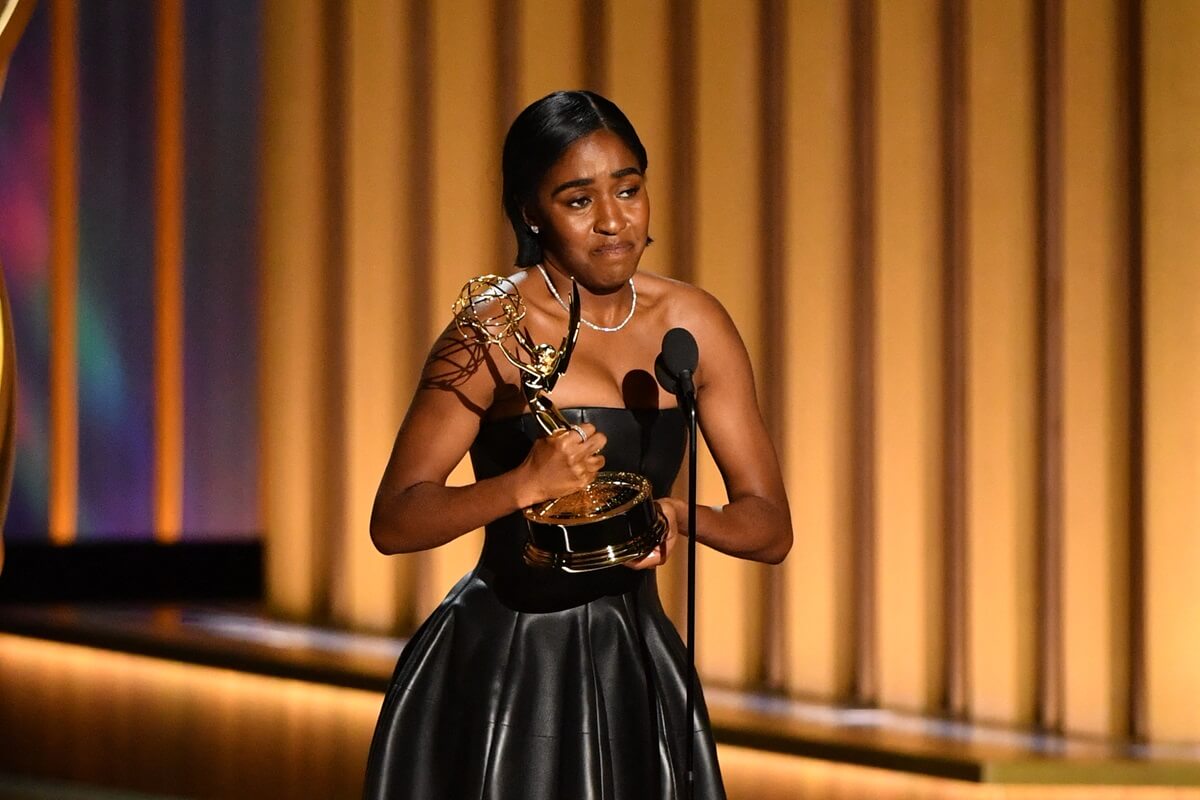 Ayo Edebiri accepting her Emmy Award while wearing a black leather dress.