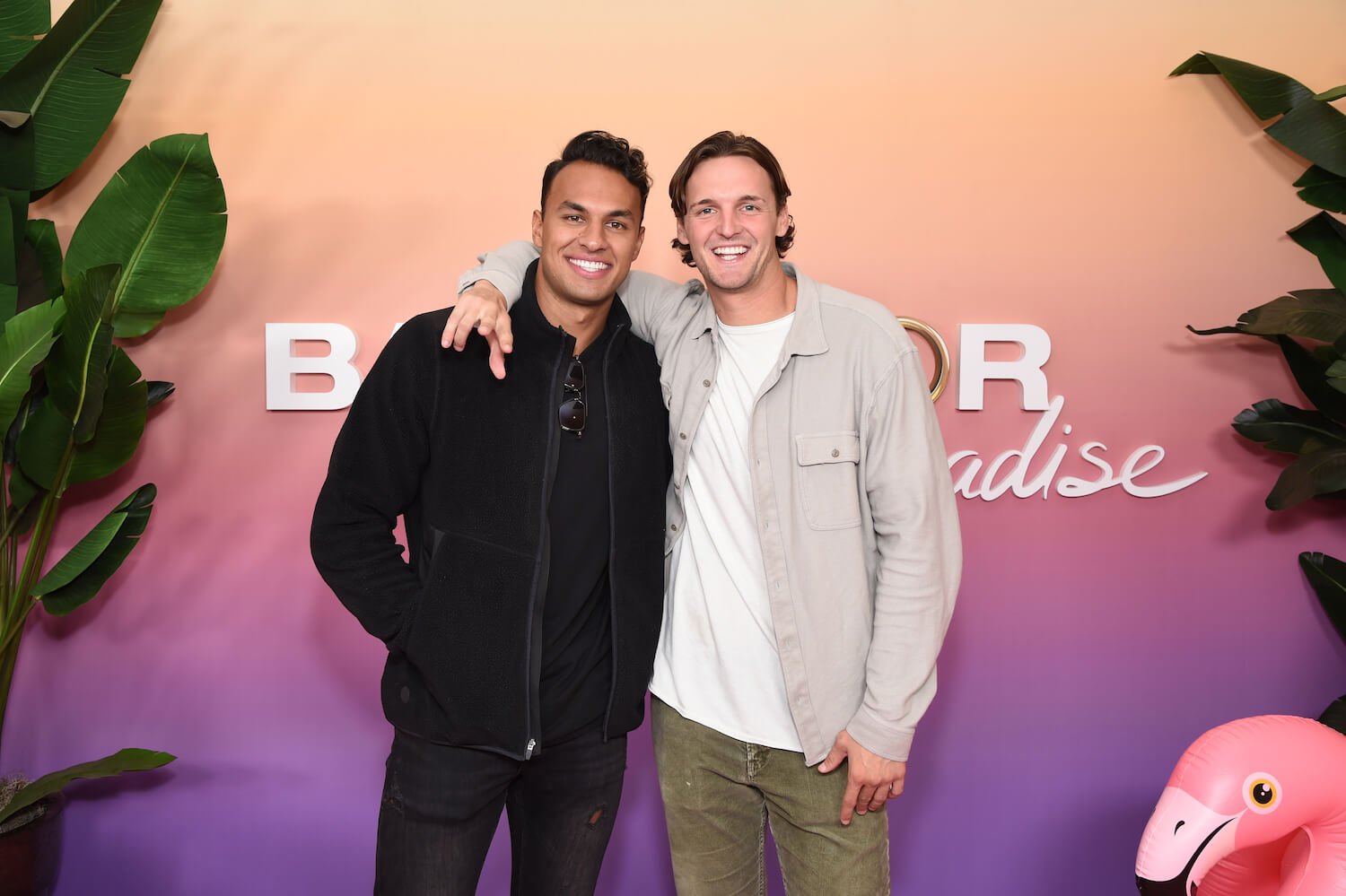 Logan Palmer and Aaron Clancy posing together in front of a 'Bachelor in Paradise' backdrop 