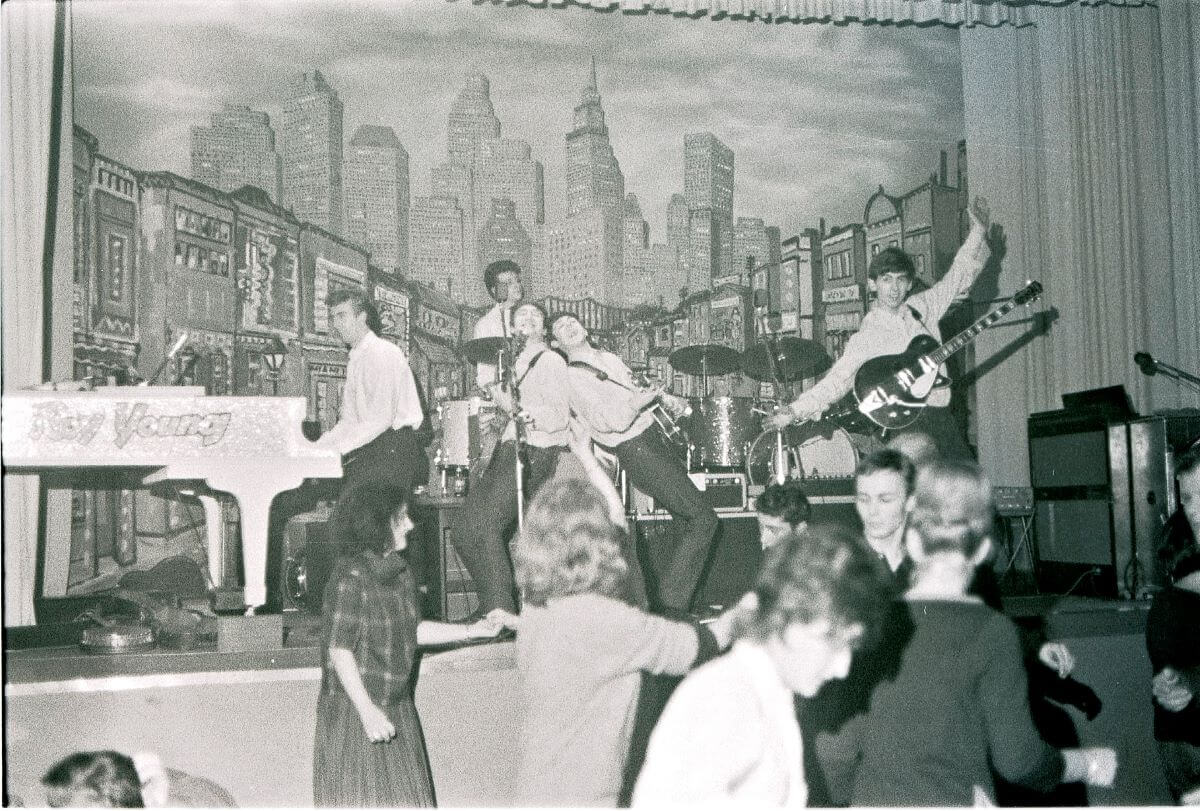 A black and white picture of The Beatles performing in front of a crowd in Hamburg.