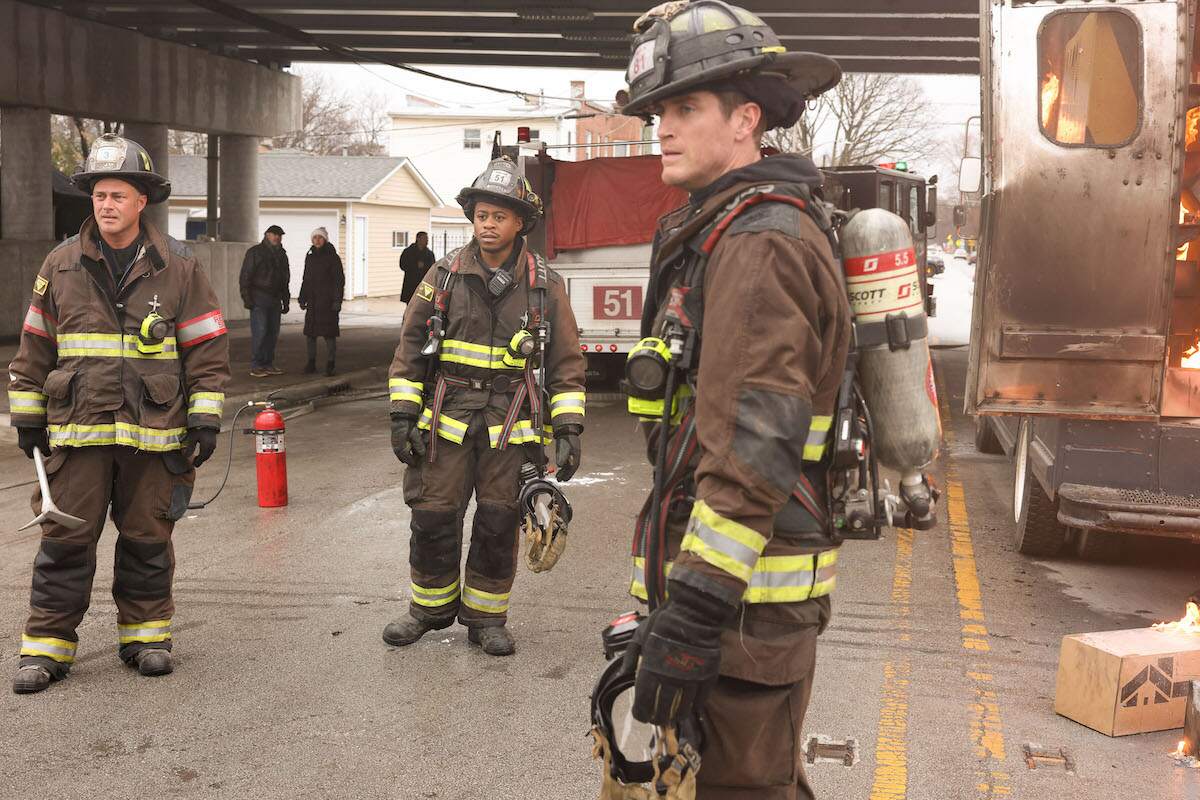 The Chicago Fire cast stands next to their fire truck during a fire