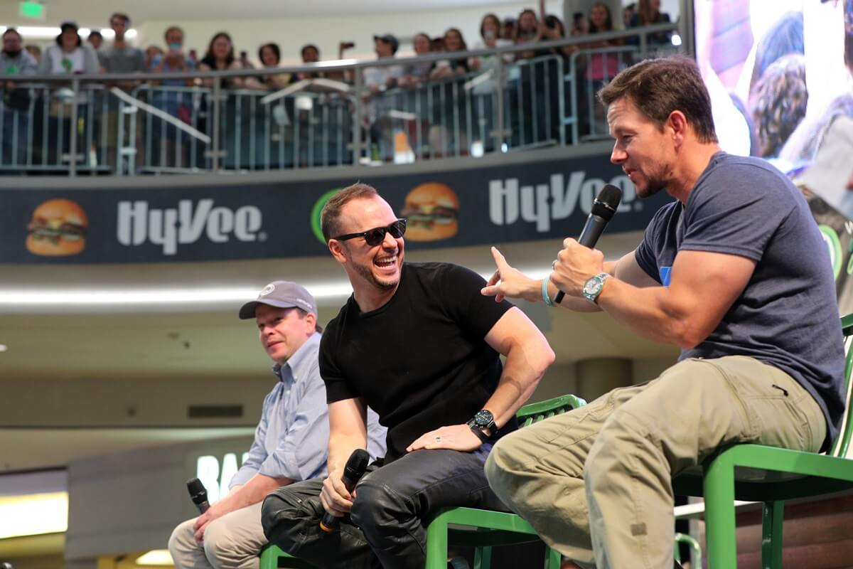 Mark Wahlberg sitting next to his brother Donnie Wahlberg at the grand opening of their Wahlburger restaurant at Mall of America.