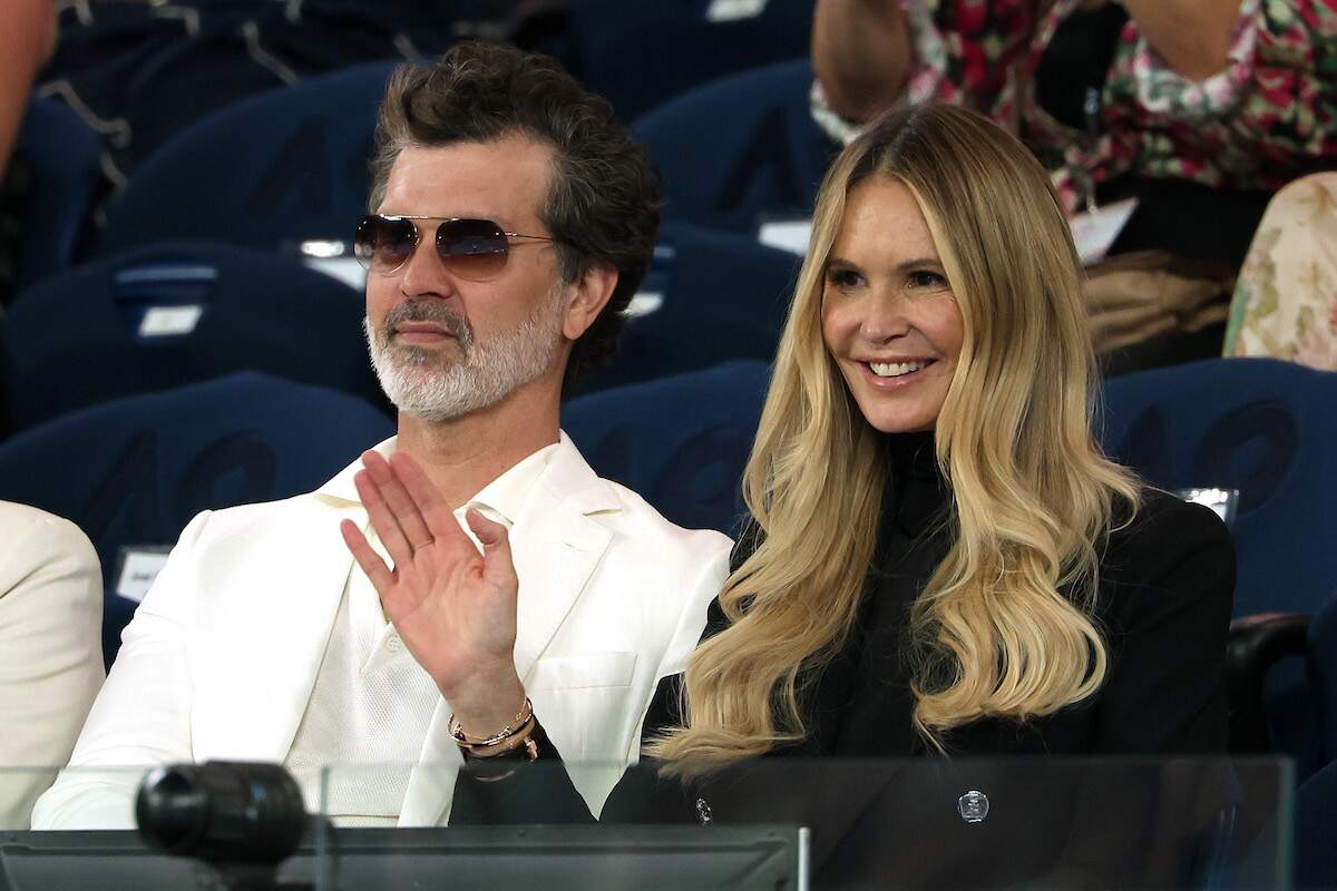 Doyle Bramhall and Elle Macpherson wave to spectators as they watch the 2024 Australian Open from the stands