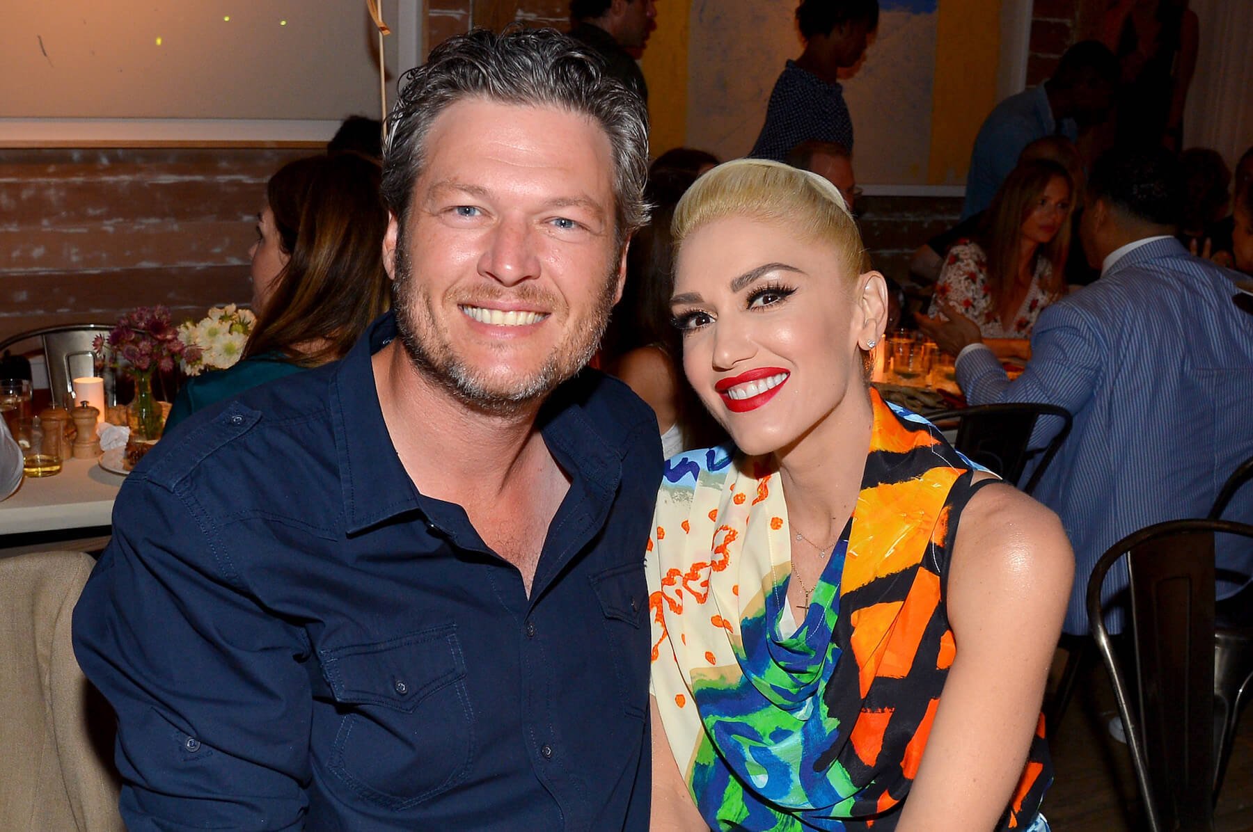 Gwen Stefani and Blake Shelton sitting next to each other and smiling for a photo