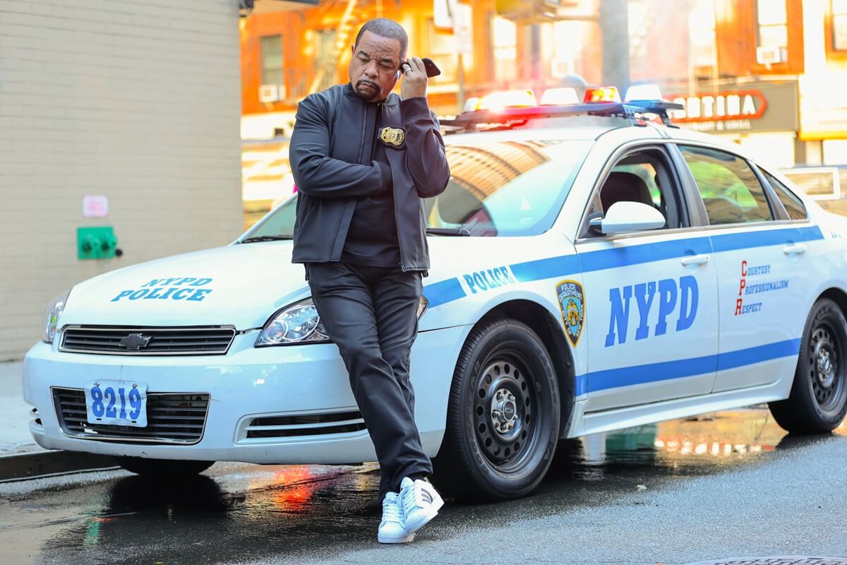 Ice-T leaning on a cop car in character on an episode of 'Law and Order: SVU'.