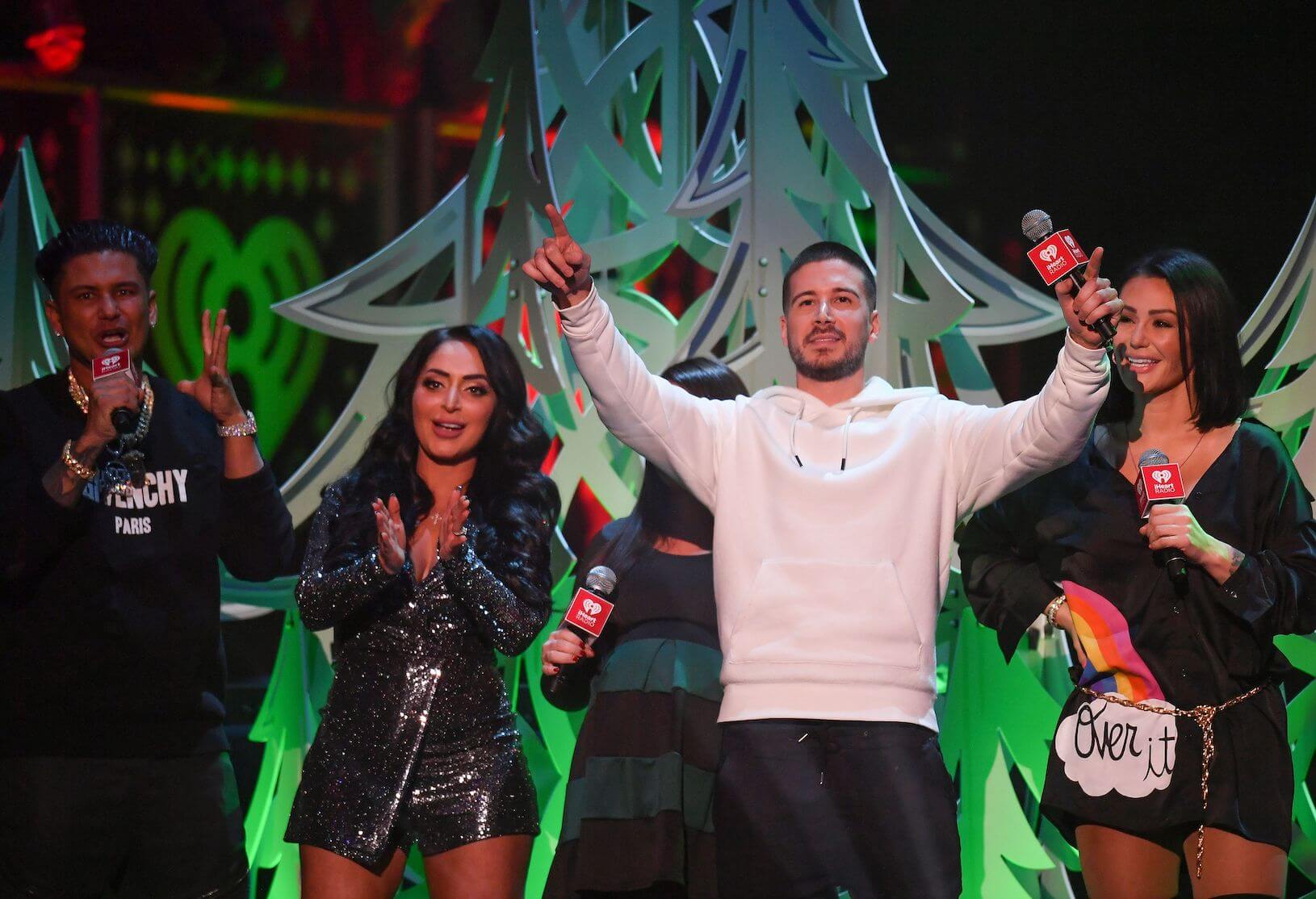 Pauly D, Angelina Pivarnick, Deena Nicole, Vinny Guadagino, and Jenni Farley from 'Jersey Shore: Family Vacation' standing on stage in front of Christmas tree decorations