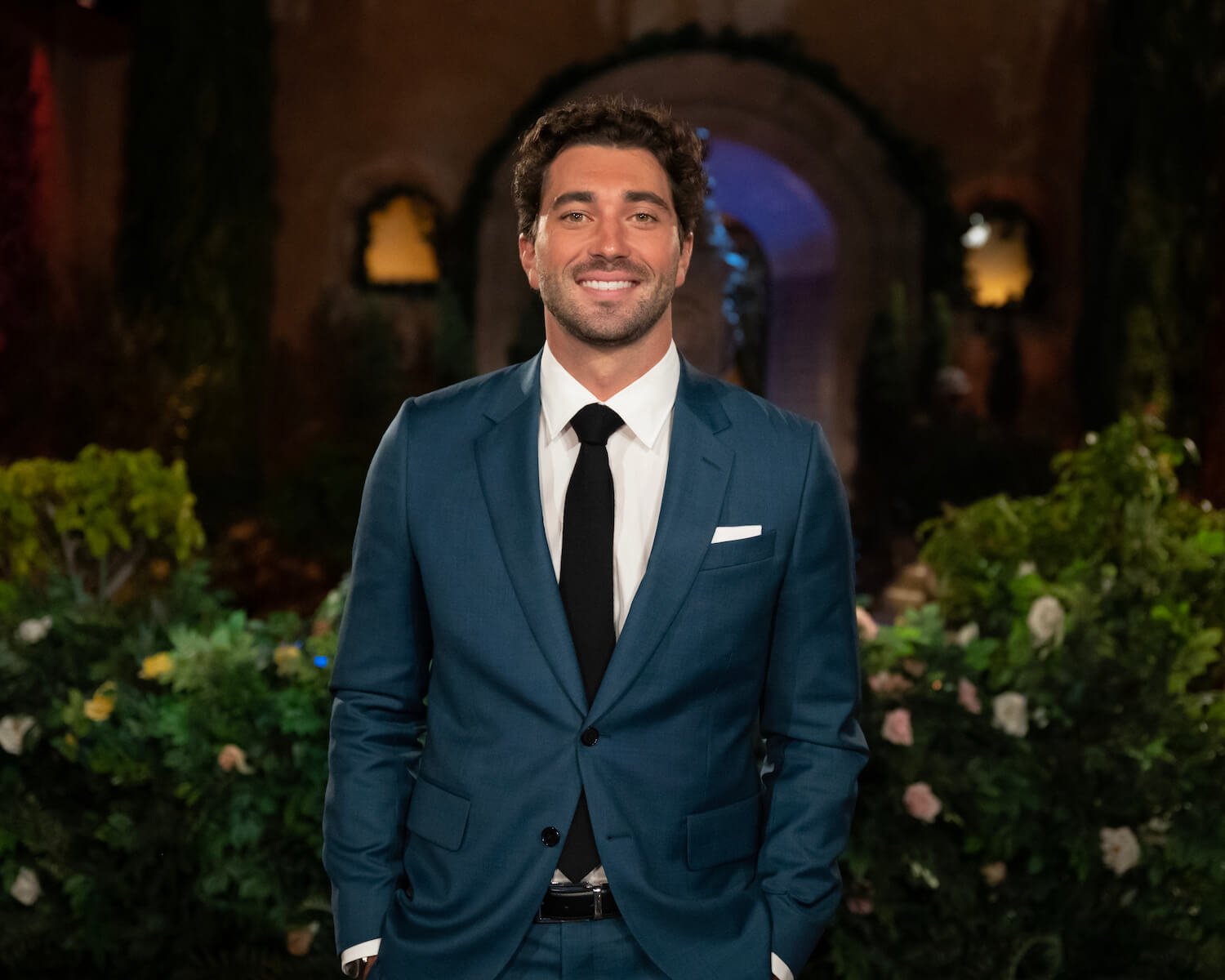 'The Bachelor' 2024 lead Joey Graziadei smiling in a suit at night outside of the Bachelor Mansion
