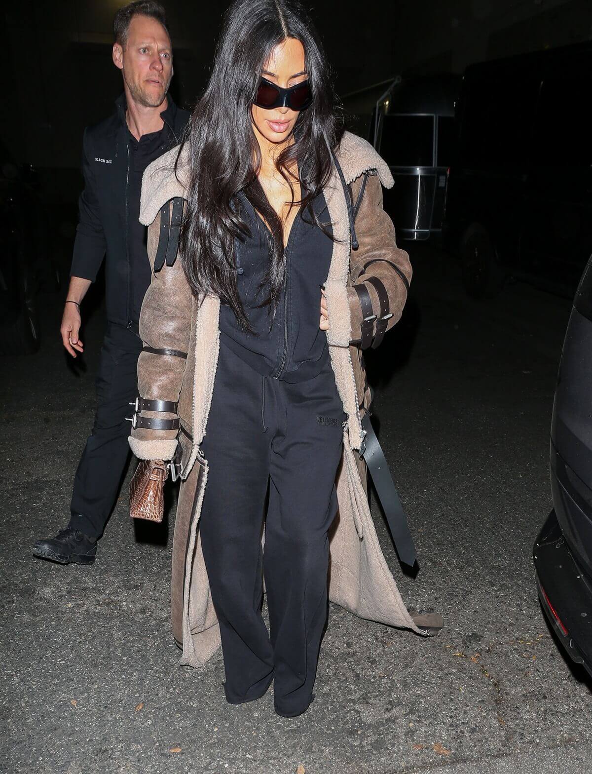 Kim Kardashian walking the streets wearing a Shearling Sheep Coat and holding a cell phone.