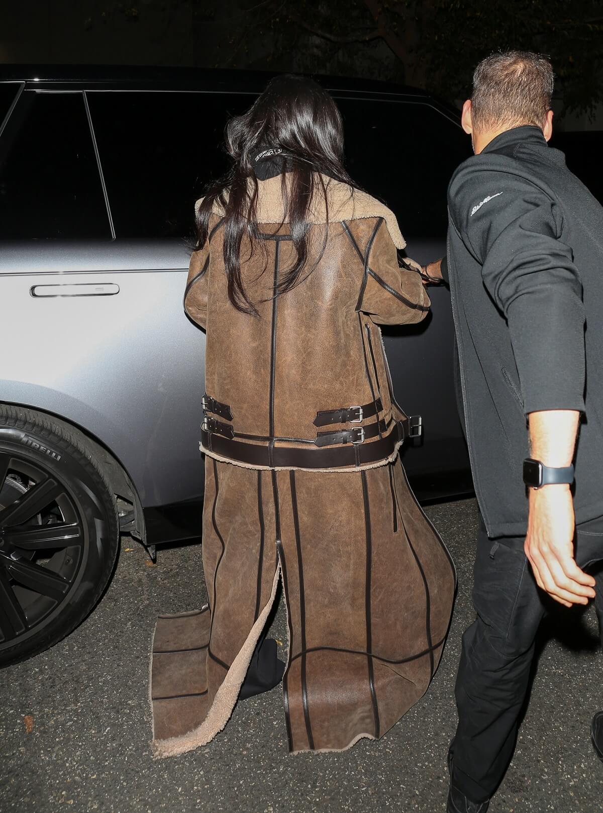 Kim Kardashian walking the streets wearing a Shearling Sheep Coat and holding a cell phone.