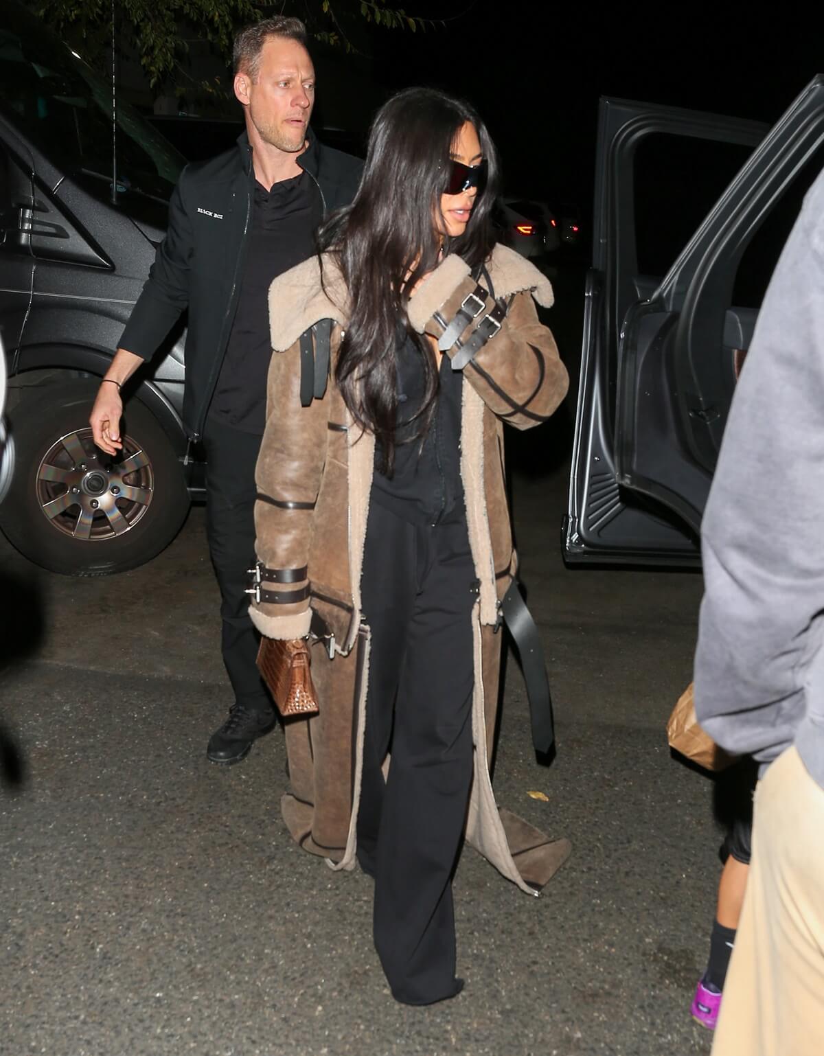 Kim Kardashian walking the streets wearing a Shearling Sheep Coat and holding a cell phone.