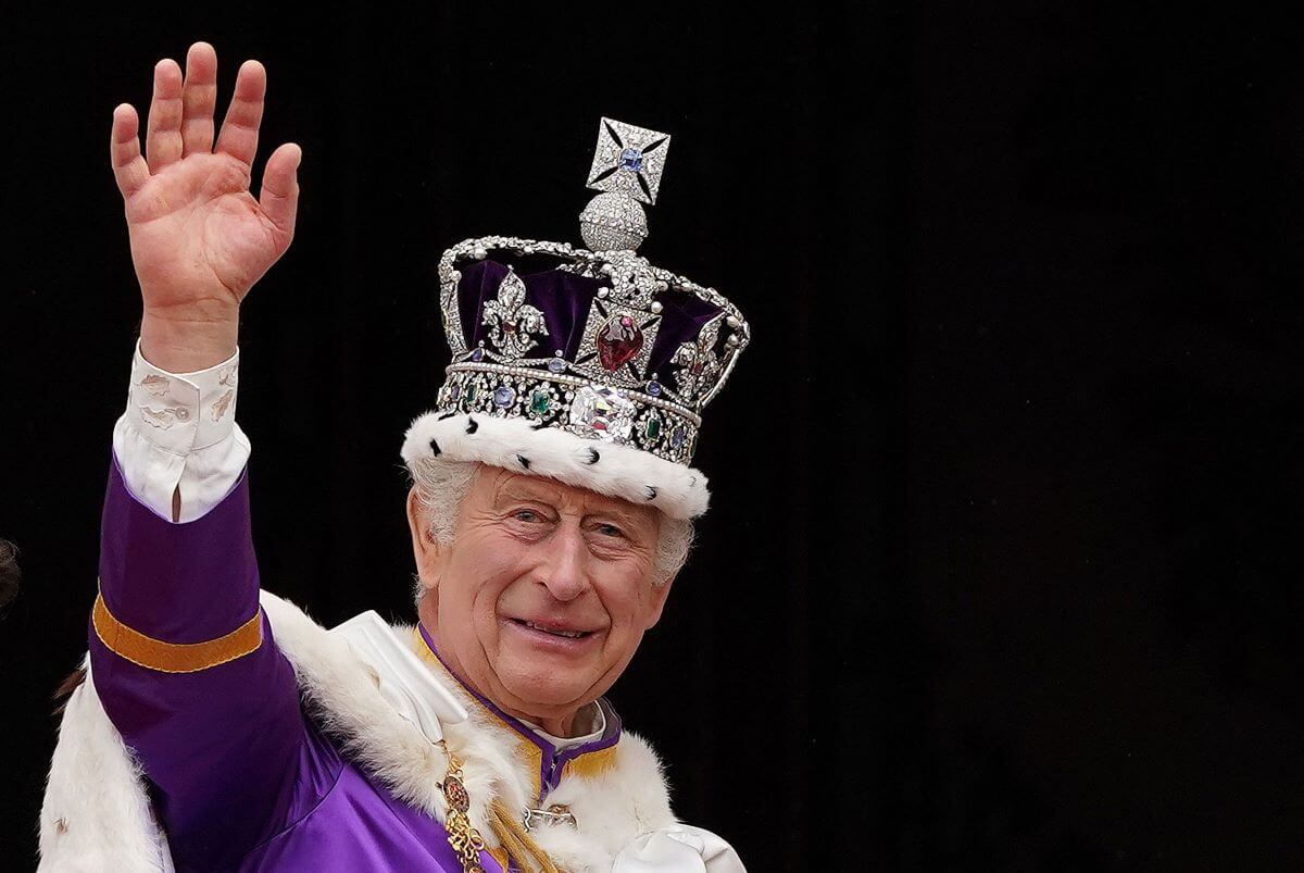 King Charles III wearing the Imperial state crown after his coronation waves from the Buckingham Palace balcony