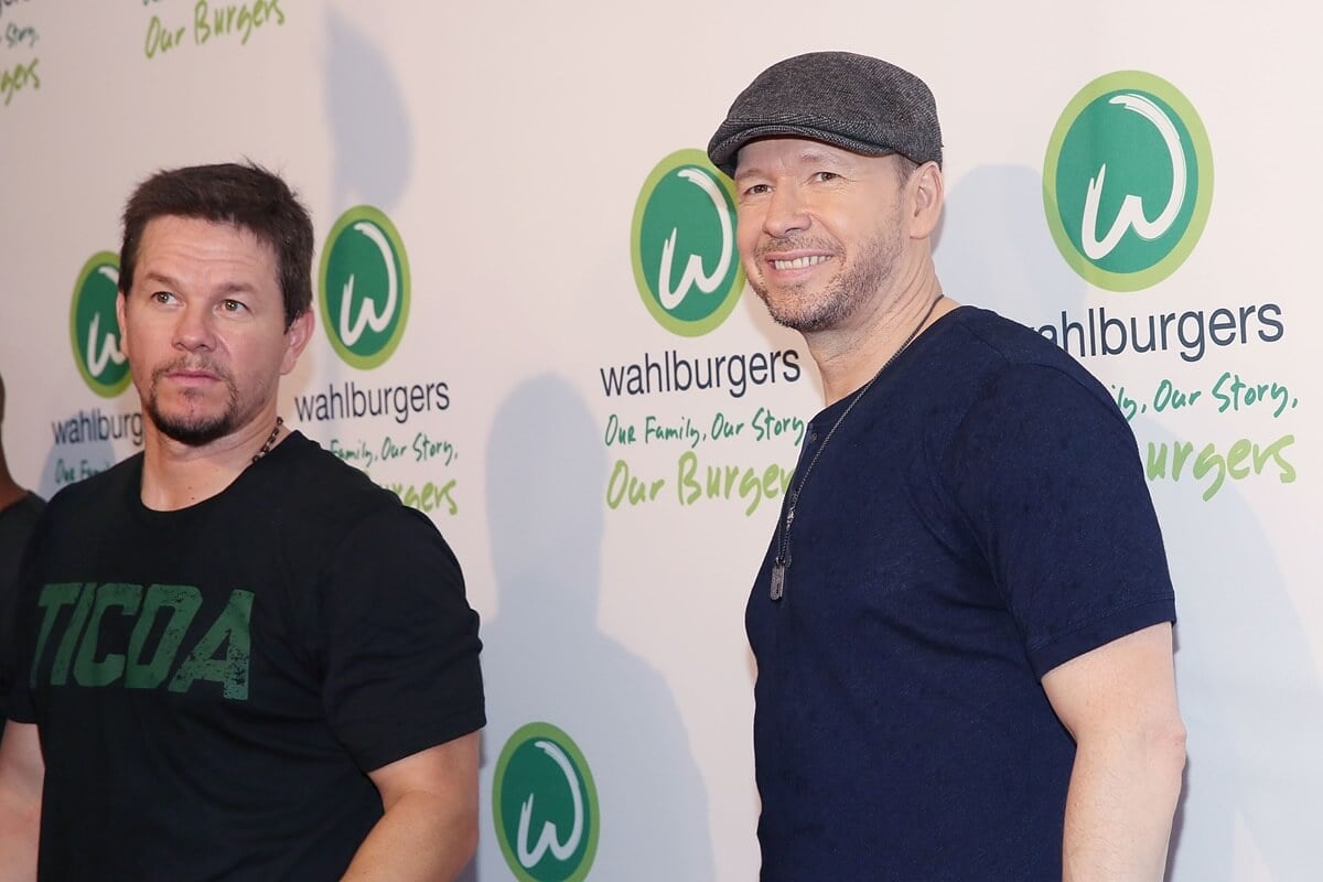 Mark Wahlberg and Donnie Wahlberg posing at the Wahlburgers Coney Island VIP wearing black and blue t-shirts.