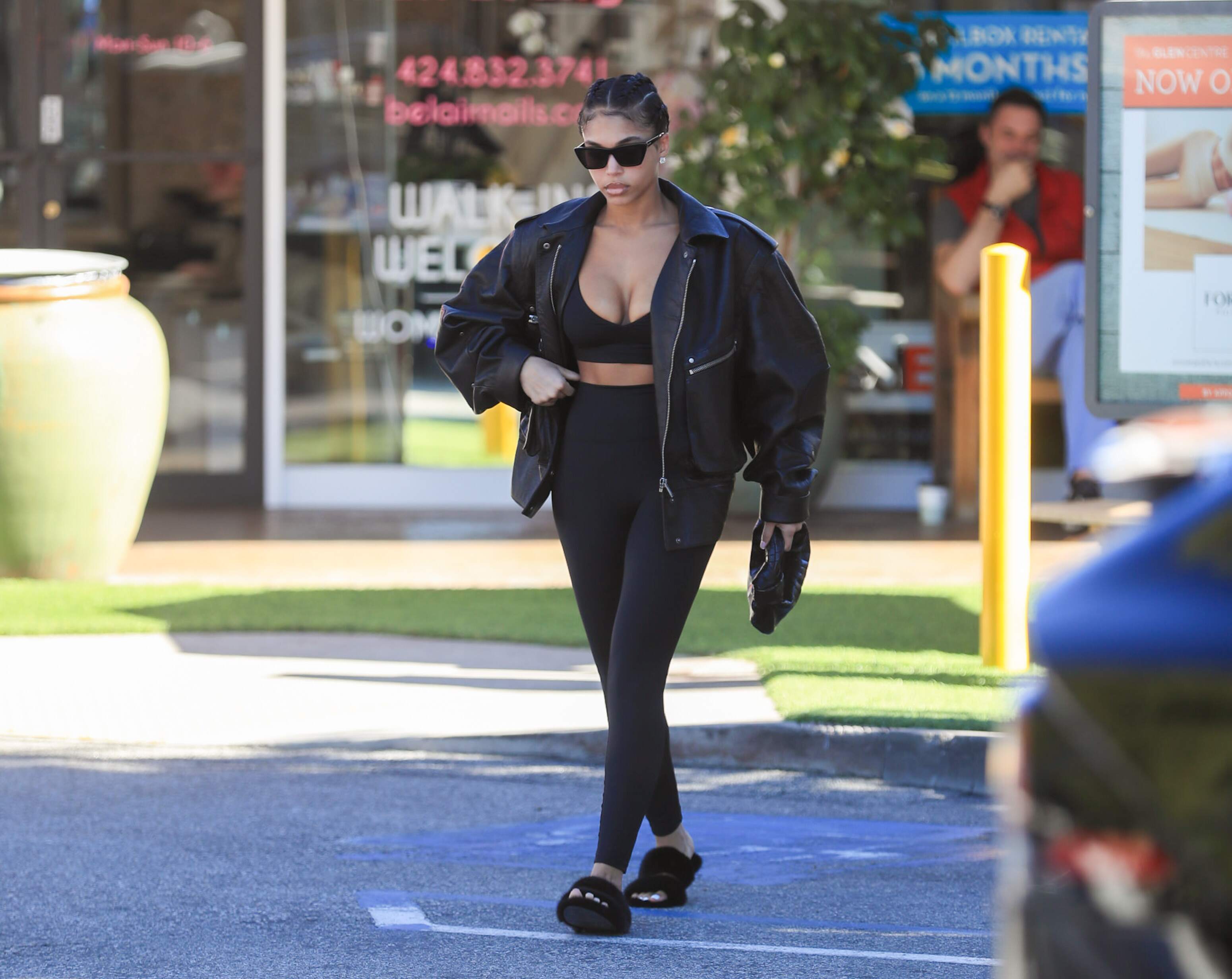 Model Lori Harvey picks up an iced coffee on a sunny day in LA while wearing a leather jacket and black leggings