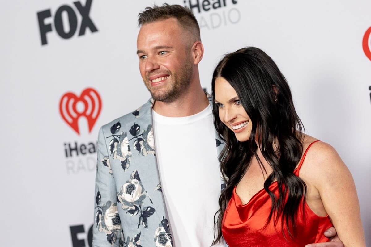 Nick Thompson posing next to Danielle Ruhl Danielle Ruhl at the 2022 iHeartRadio music awards at Shrine Auditorium and Expo Hall in a white t-shirt and light grey jacket.