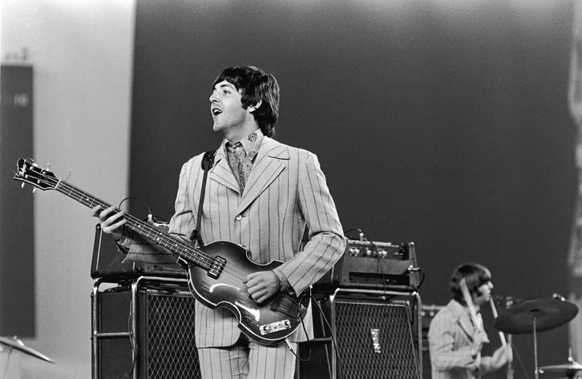 A black and white picture of Paul McCartney standing onstage with a bass guitar.
