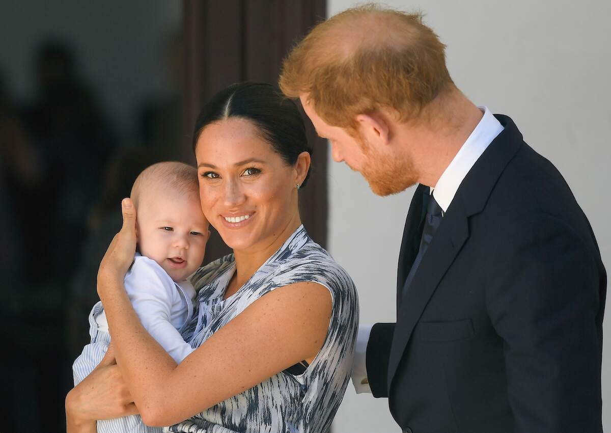 Meghan Markle holds baby Archie while smiling as Prince Harry looks on