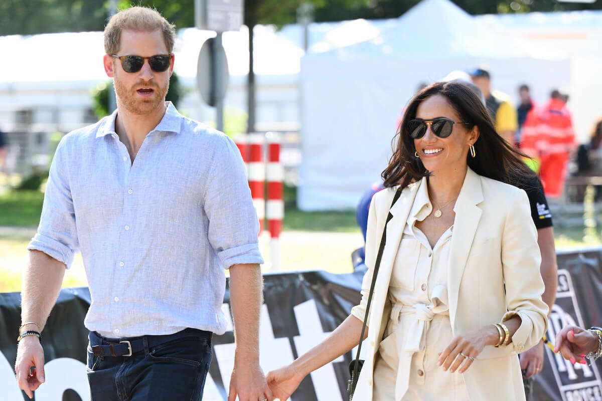 Prince Harry and Meghan Markle walk side-by-side and hold hands.