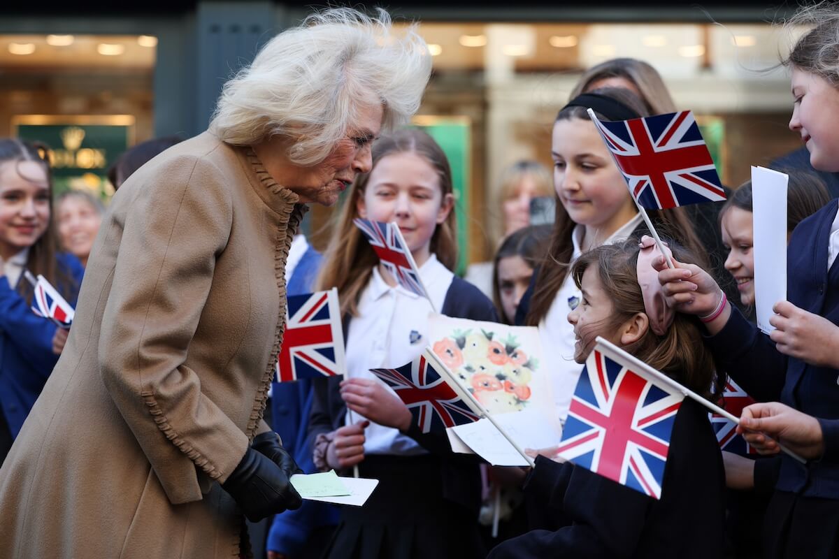 Queen Camilla greeting young girls holding UK flags