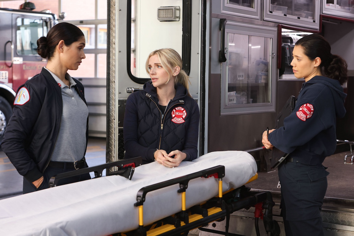 Stella, Brett, and Violent standing around an empty stretcher in the 'Chicago Fire' Season 12 premiere