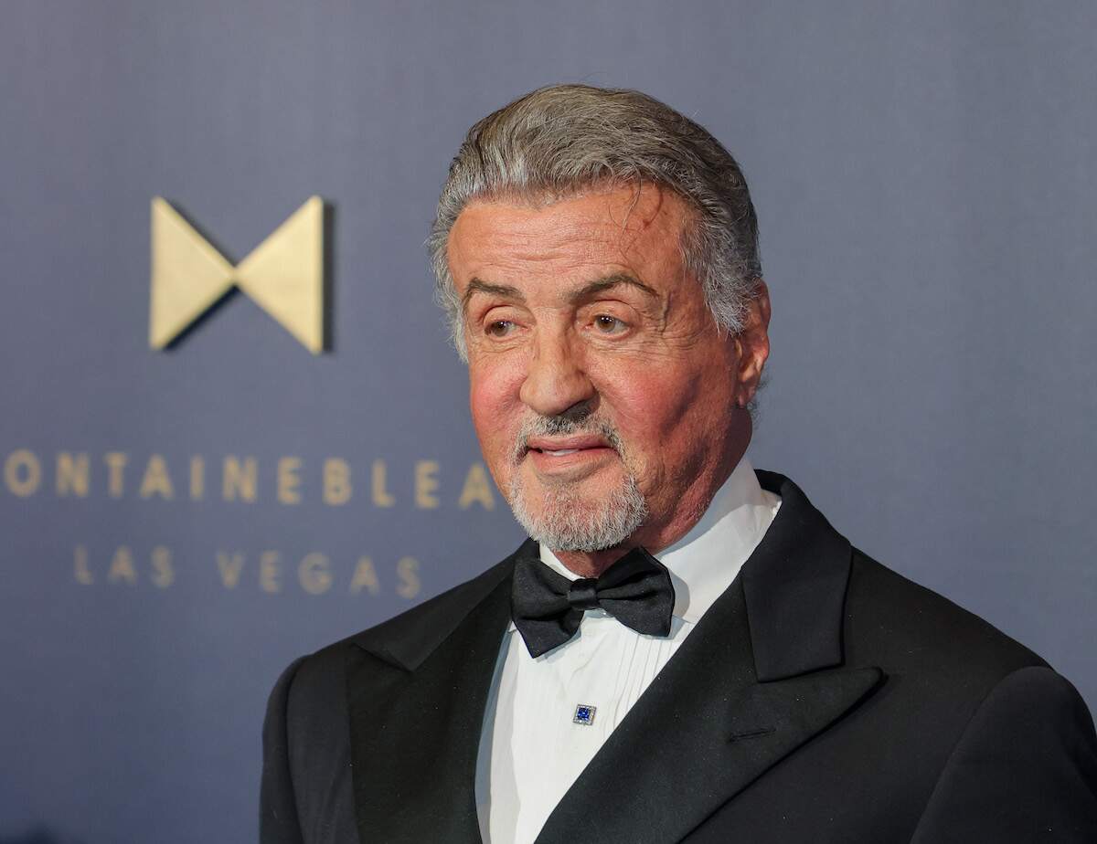 Actor Sylvester Stallone wears a tuxedo and smiles on a red carpet in 2023