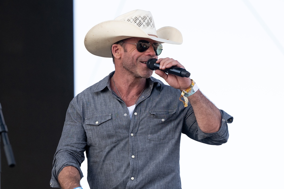 Taylor Sheridan wearing a white cowboy hat and holding a microphone