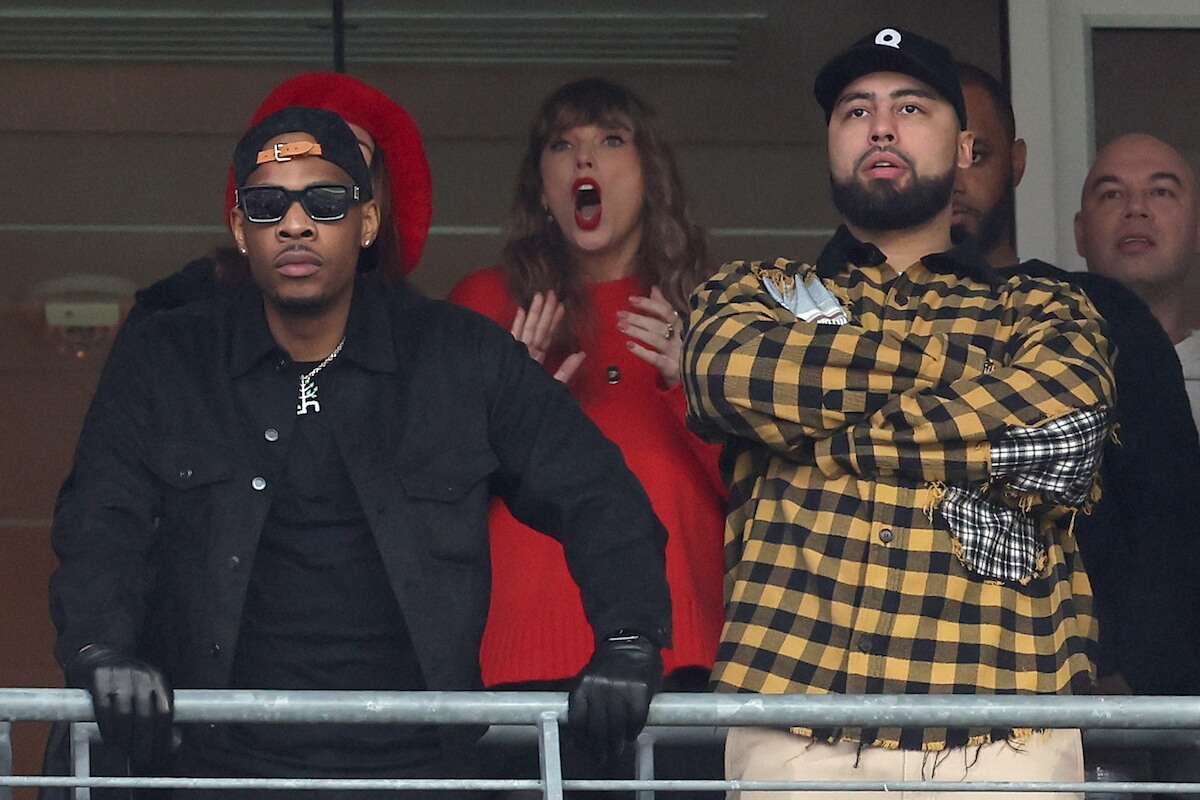 Taylor Swift standing up and cheering in a luxury suite at Chiefs game