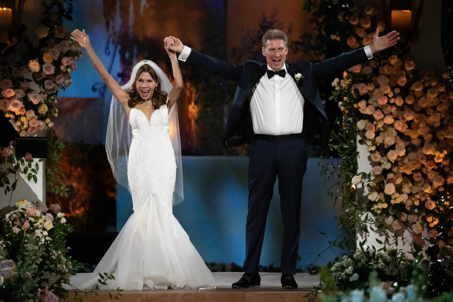 'The Golden Bachelor' wedding with Theresa Nist in a wedding gown and Gerry Turner in a tuxedo. They appear excited with their arms raised.