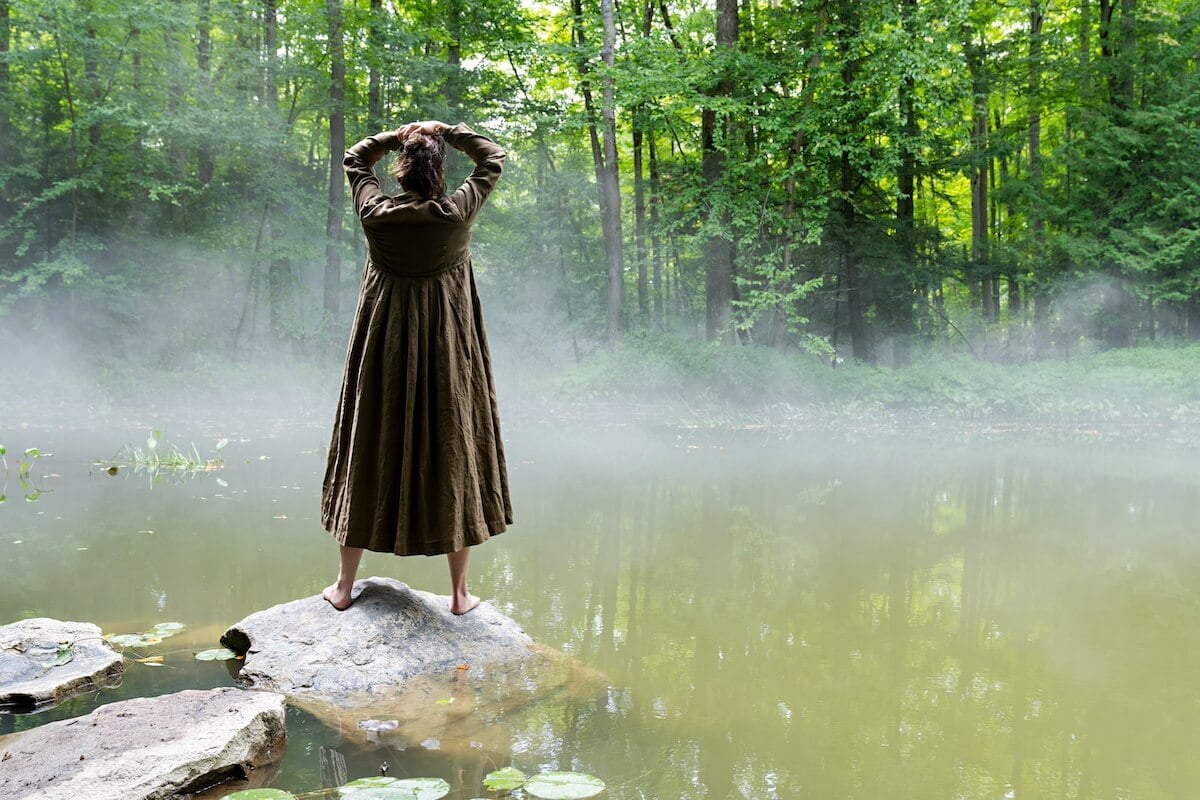 Kat, seen from the back, stands on a rock and looks into the pond in 'The Way Home' Season 2
