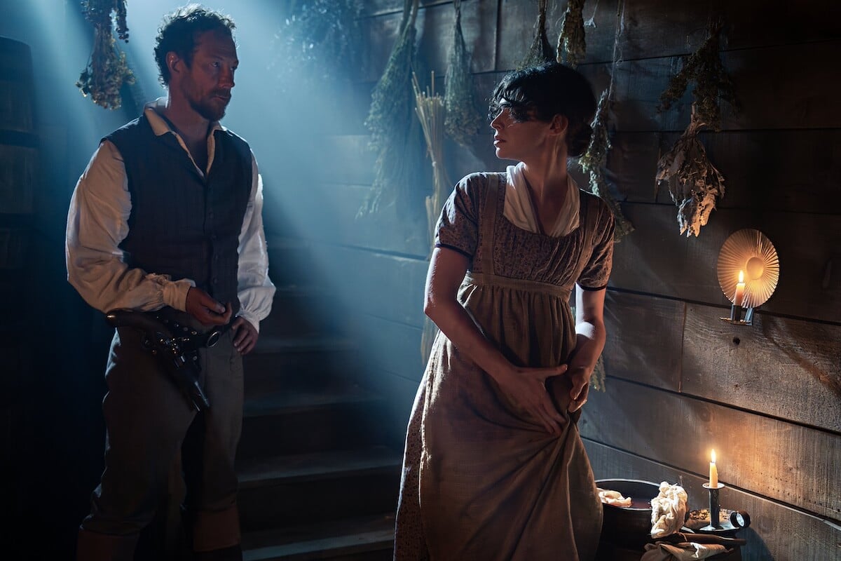 A woman in an empire-waist dress looks over a shoulder at a man in 19th century clothing in 'The Way Home' Season 2