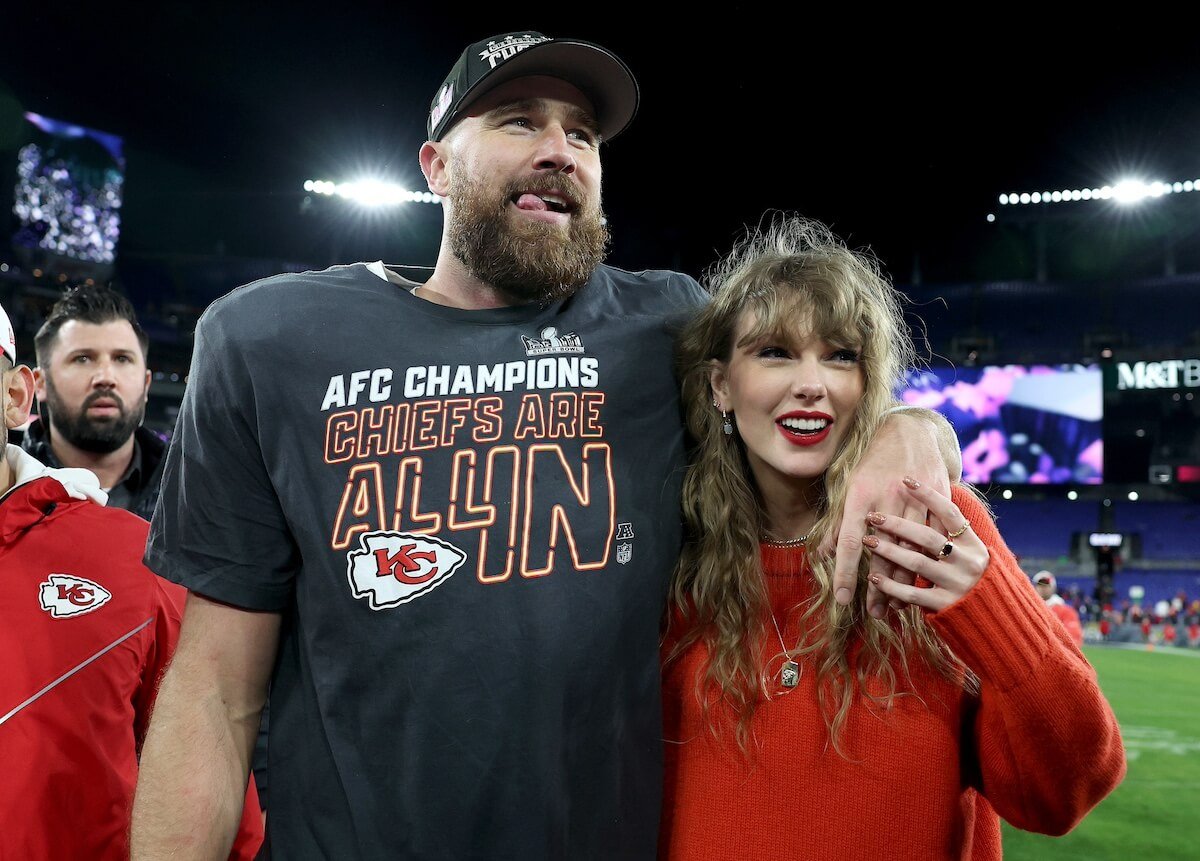 Travis Kelce, in a baseball hat, with his arm around Taylor Swift, wearing a red sweater, after the Chiefs' win on Jan. 28