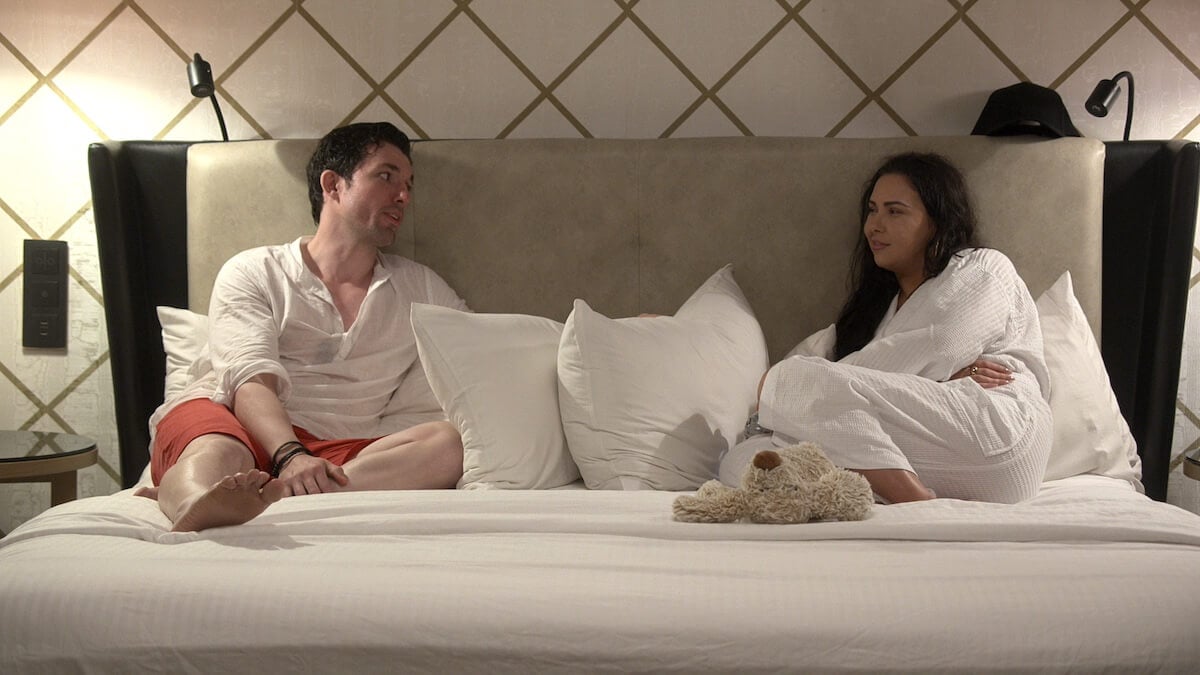 Zack and Bliss from 'Love Is Blind' wearing white robes and sitting on a bed