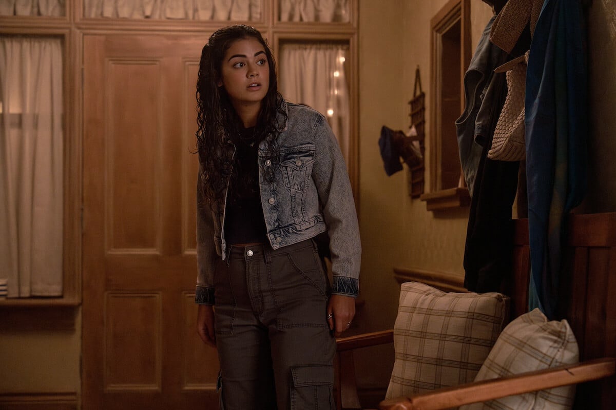 Alice, wearing a denim jacket and standing in front of a door, in 'The Way Home'