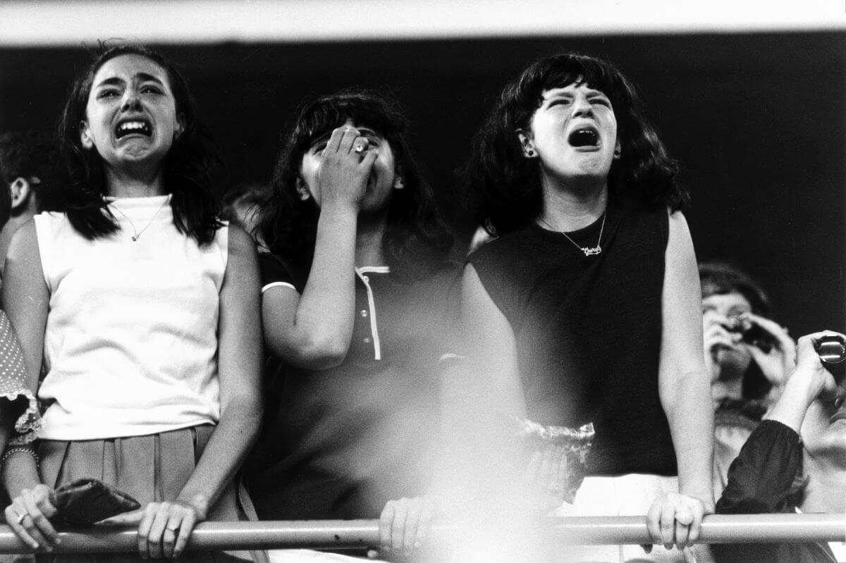 A black and white picture of Beatles fans crying at their concert.