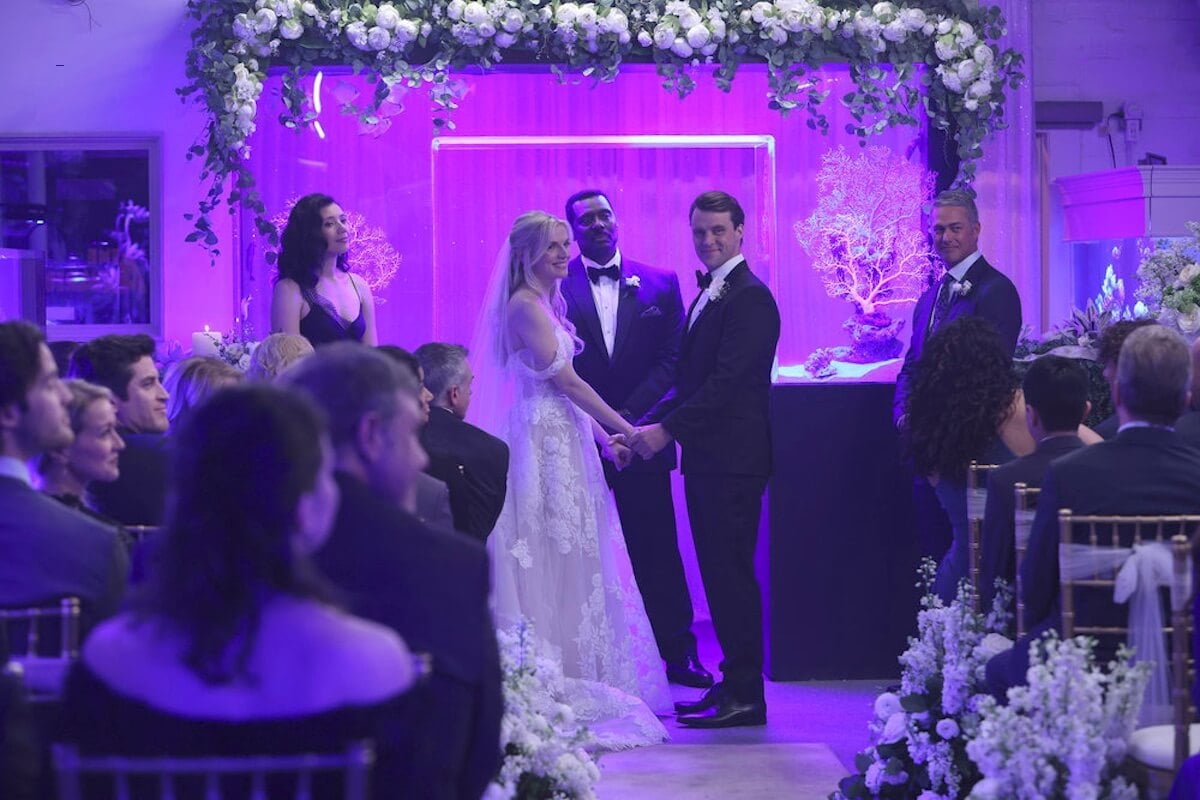 Sylvie Brett and Matt Casey standing in front of their officiant and holding hands while looking at each other on 'Chicago Fire'