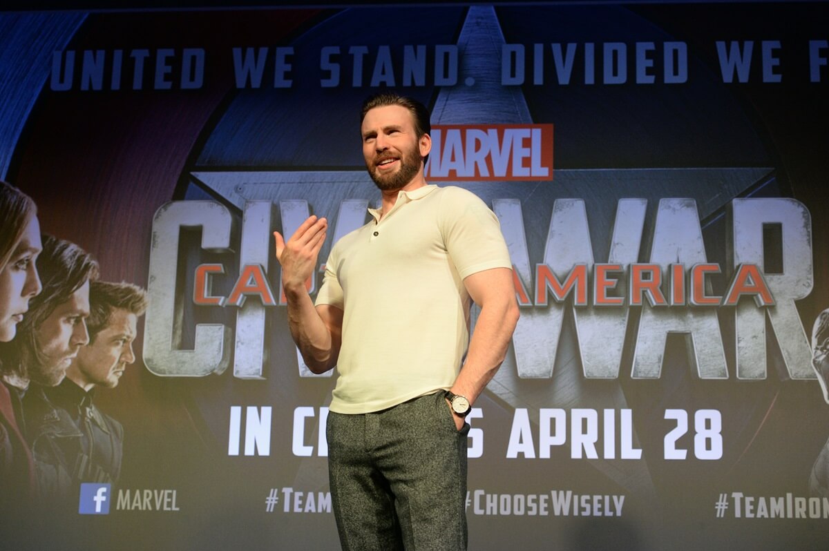 Chris Evans posing in a white shirt and grey jeans during a Marvel event.