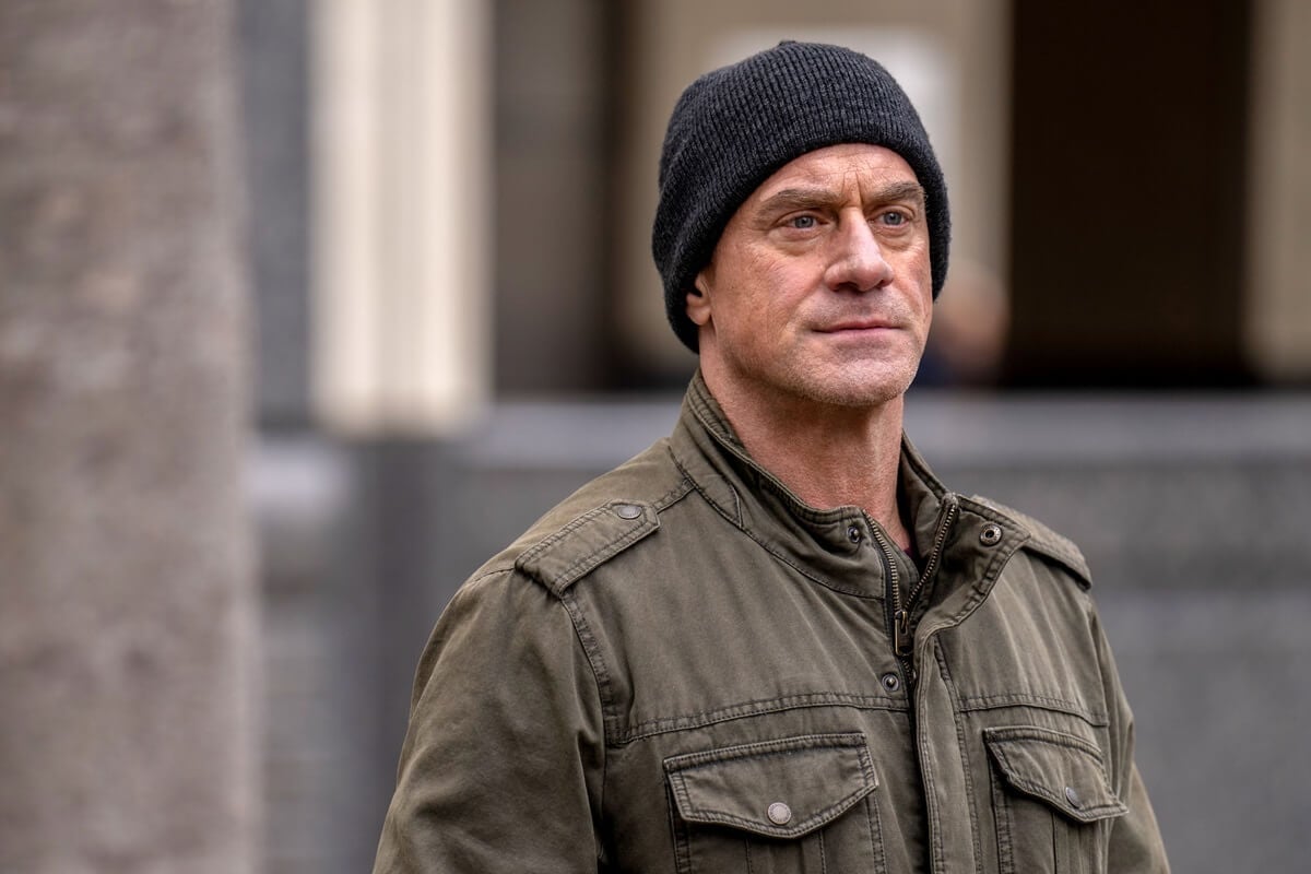 Chris Meloni posing in an episode of 'Law & Order Organized Crime' wearing a jacket and hat.