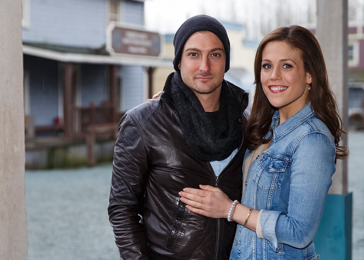 Daniel Lissing, in a knit cap, scarf, and leather jacket, and Erin Krakow, in a denim jacket, on the set of 'When Calls the Heart'