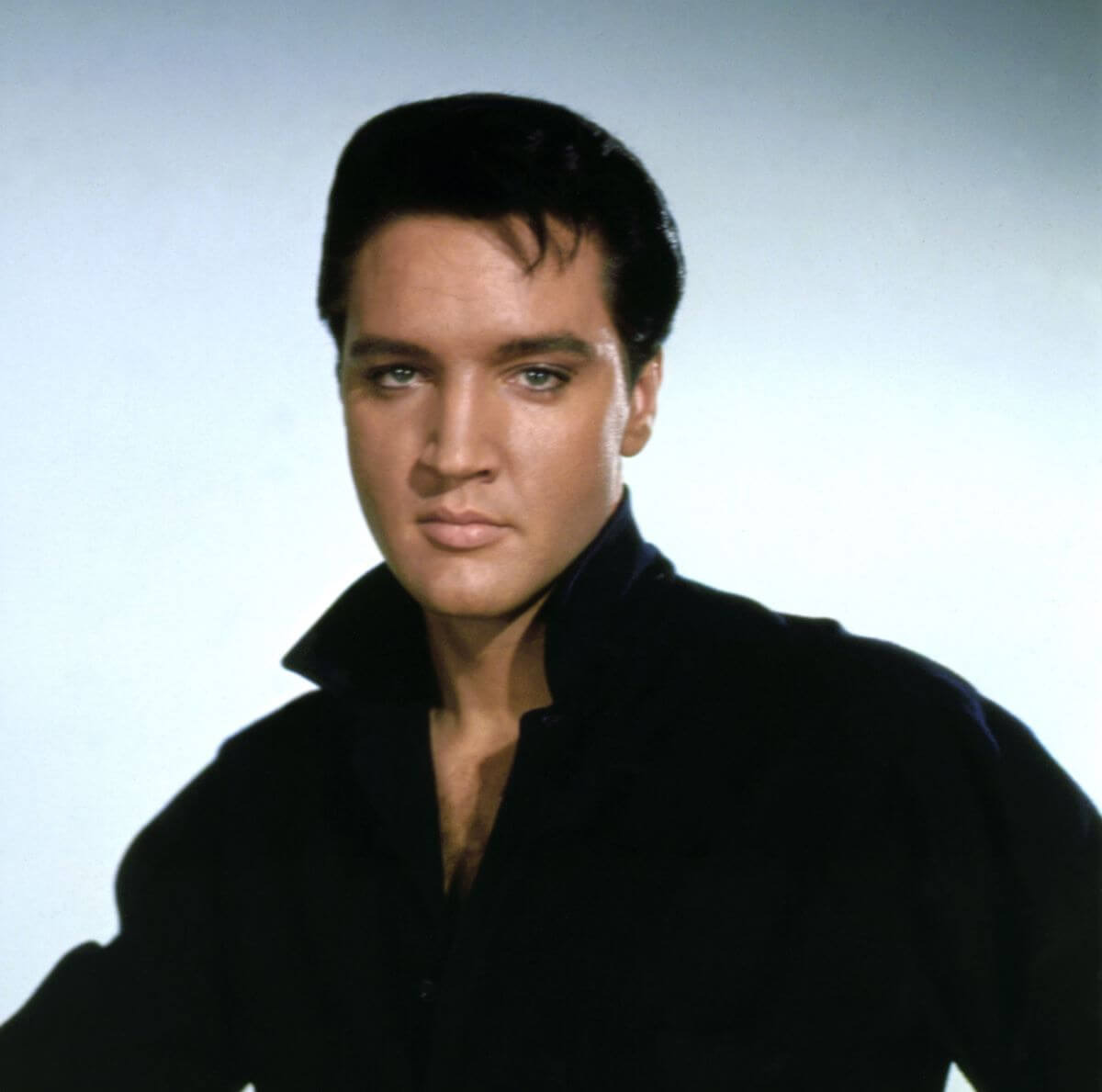 Elvis wears a black shirt with a popped collar.