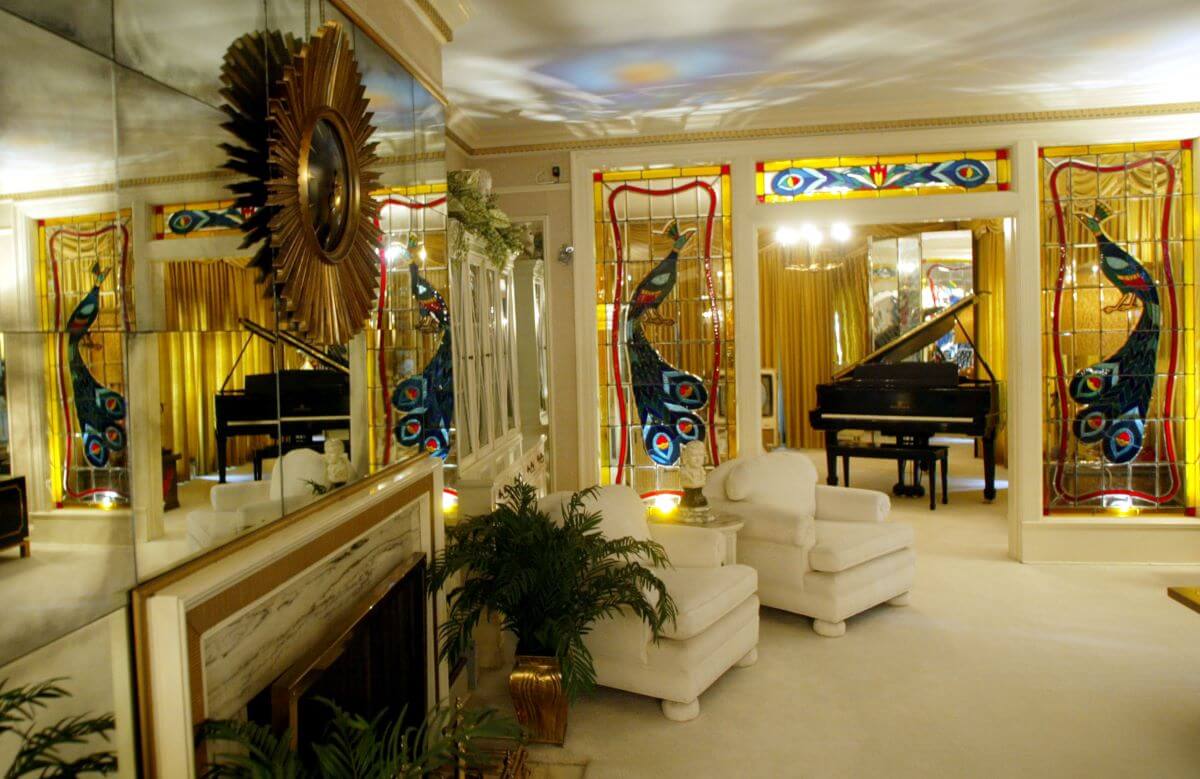 Elvis' living room at Graceland has a potted plant, two white chairs, and a piano. 