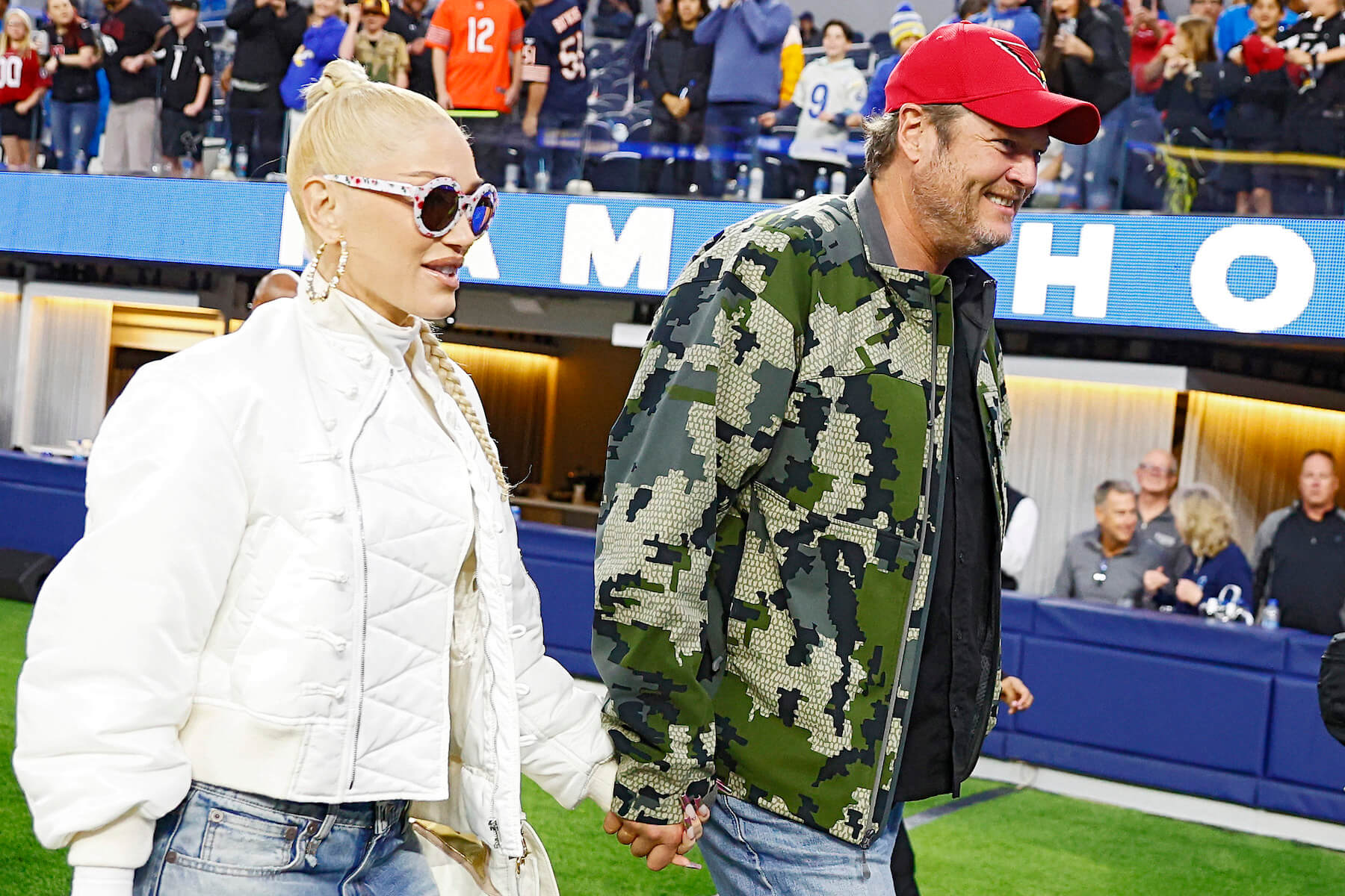 Gwen Stefani and Blake Shelton walking on a football field at a game between the Los Angeles Rams and the Arizona Cardinals