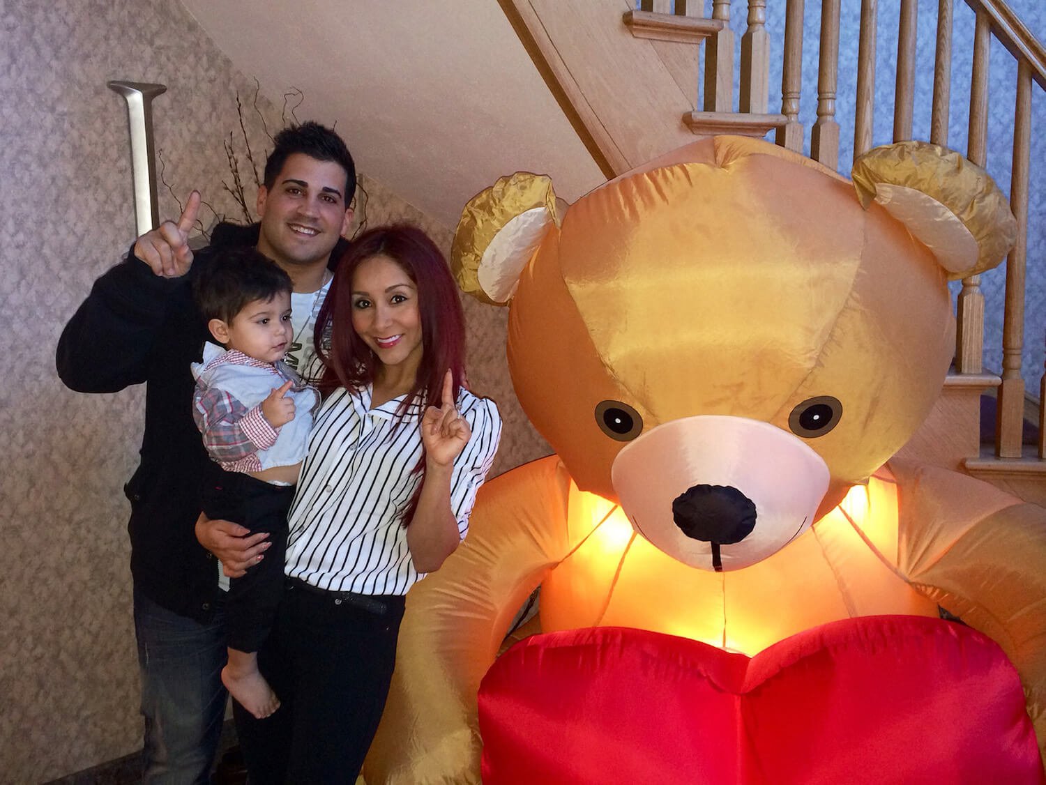 'Jersey Shore: Family Vacation star Nicole 'Snooki' Polizzi holding her son and standing next to her husband, Jionni LaValle. They're next to an inflatable bear for Valentine's Day.