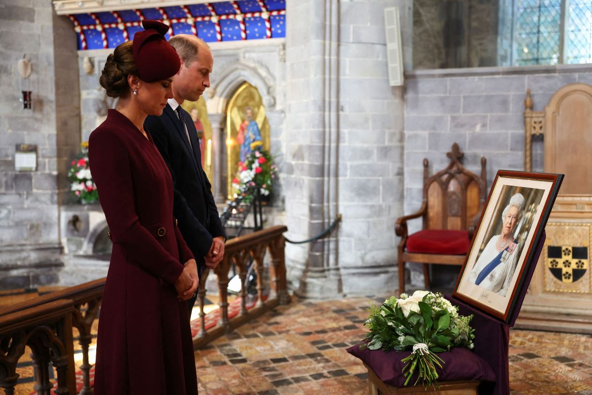 Kate Middleton and Prince William inside St. David's Cathedral looking at a photo of the late Queen Elizabeth II 