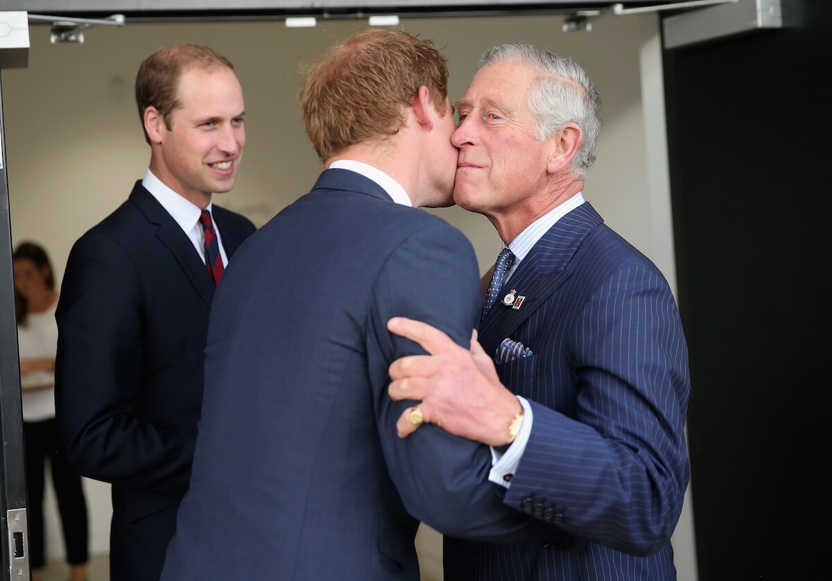 King Charles gives Prince Harry a kiss on the cheek in 2014 with Prince William