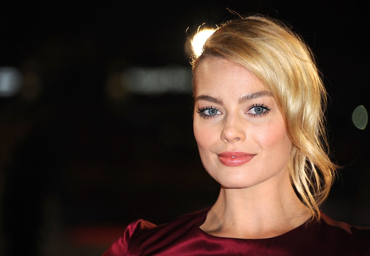 Margot Robbie posing at the 'Wolf of Wall Street' premiere while wearing a dark red dress.