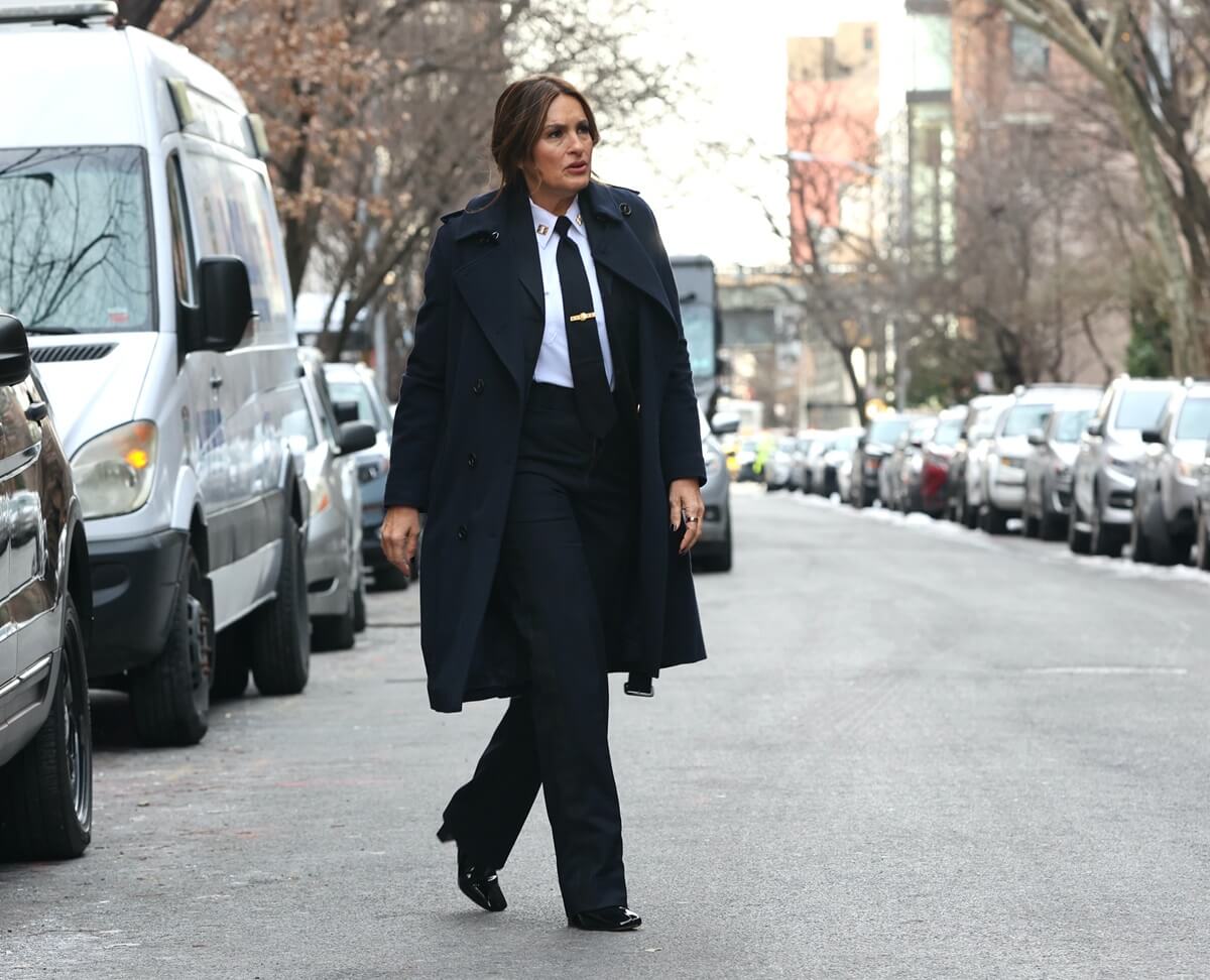 Mariska Hargitay walking in a suit and trench coat on the set of "Law and Order: Special Victims Unit".