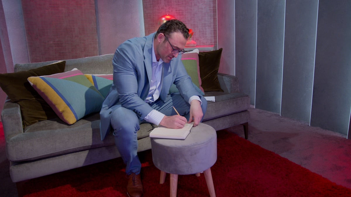 Matthew writing in his notebook in one of the 'Love Is Blind' pods